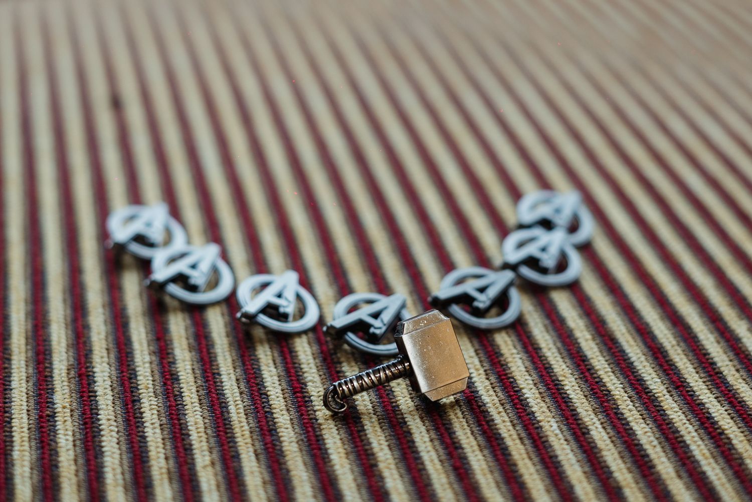 Close-up of decorative Celtic knot cufflinks and a gold tie bar arranged on a striped fabric surface.