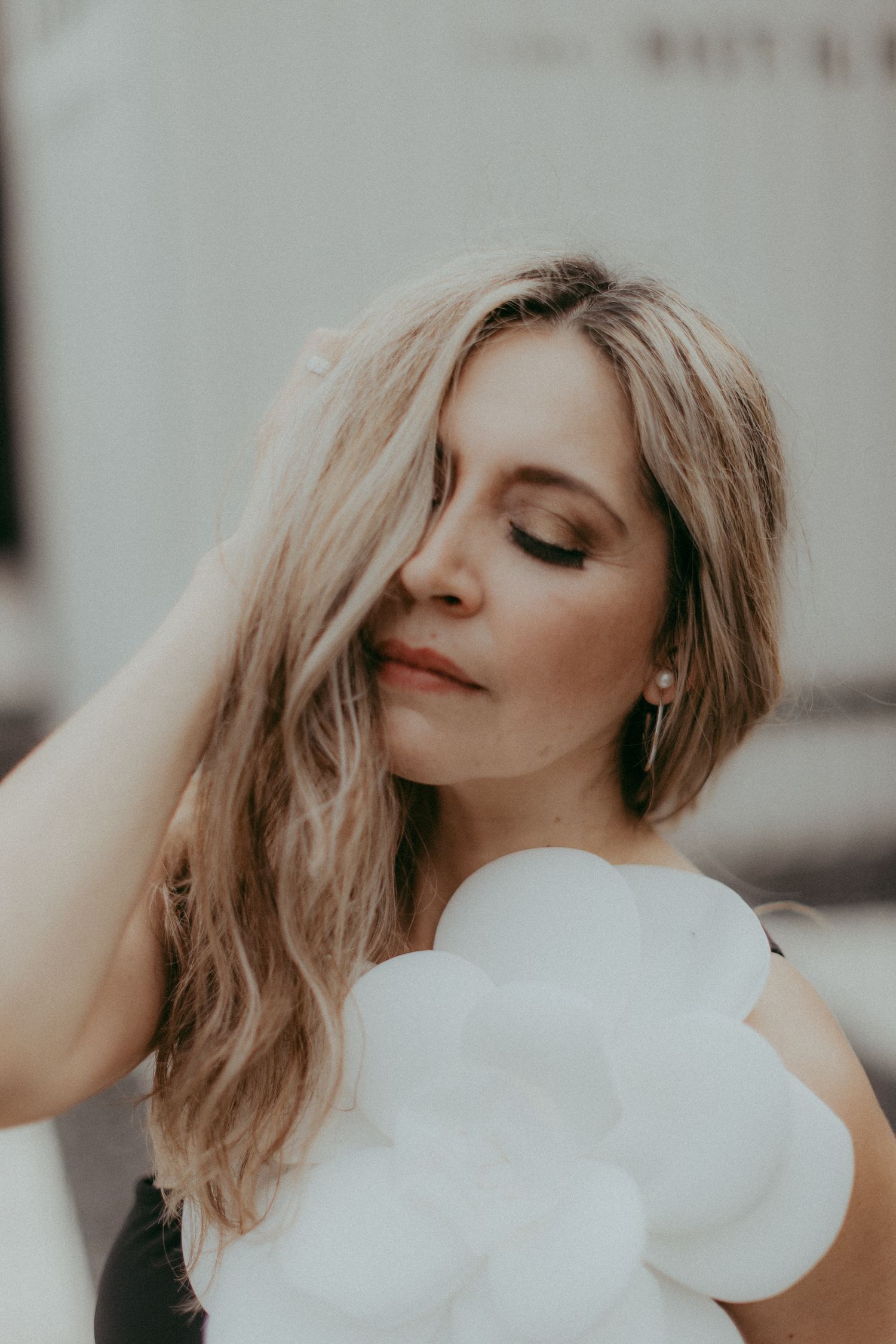 Dreamy portrait showing long blonde hair and white balloons in soft muted tones.