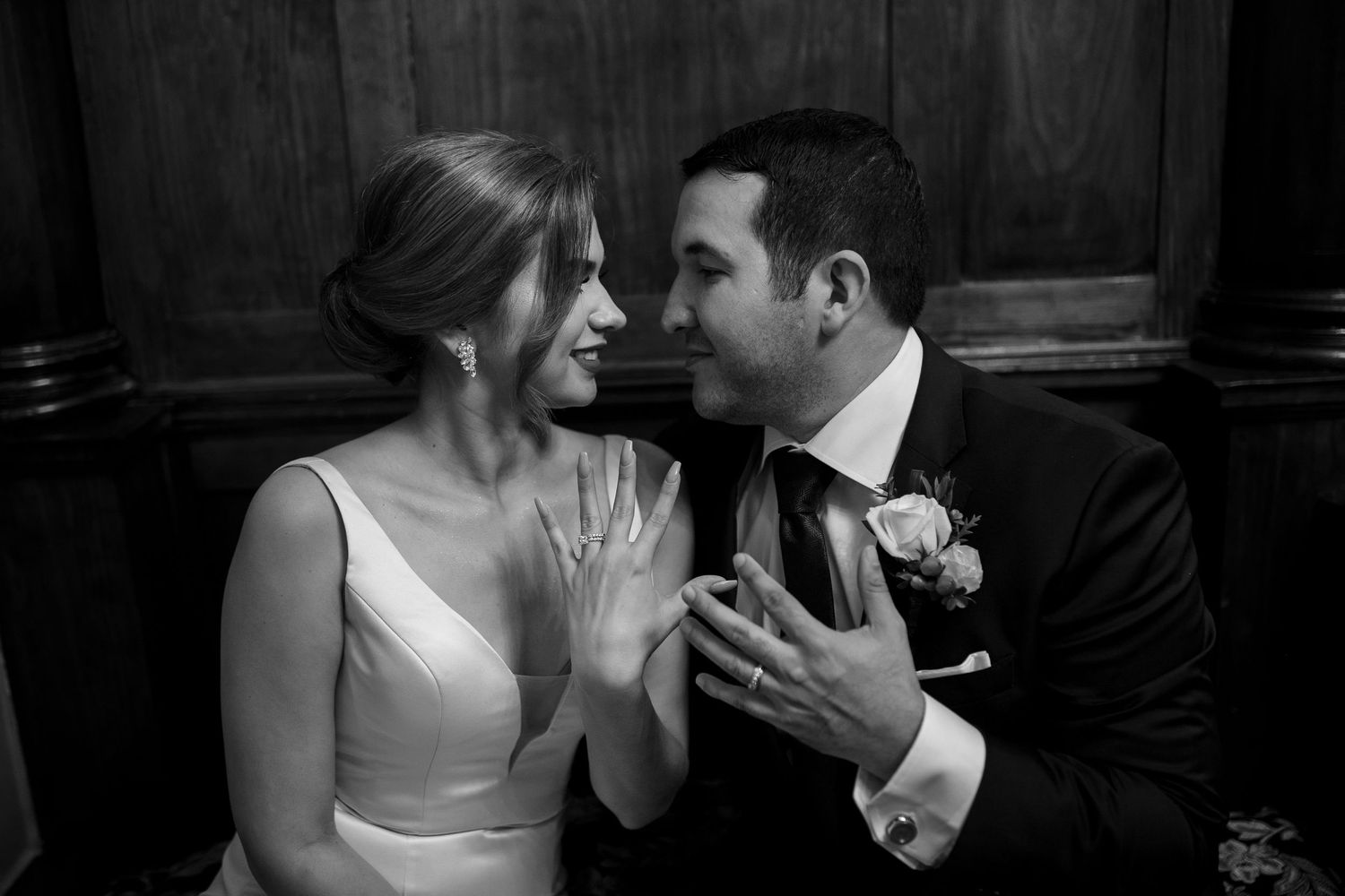 Black and white photo of bride and groom sharing a tender moment, bride showing off her wedding ring.
