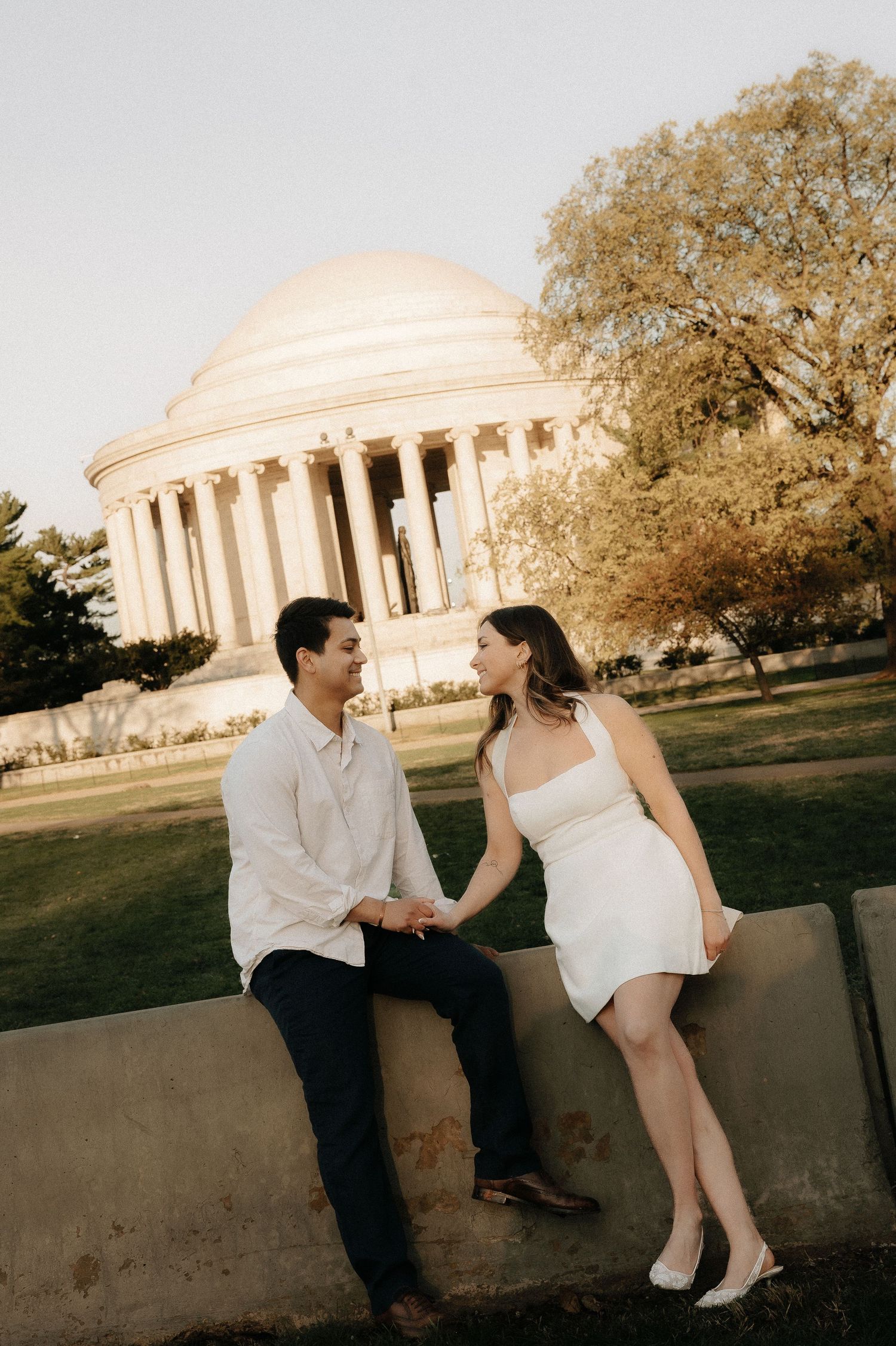 Couple holding hands and smiling at each other in front of the Jefferson Memorial in Washington DC.