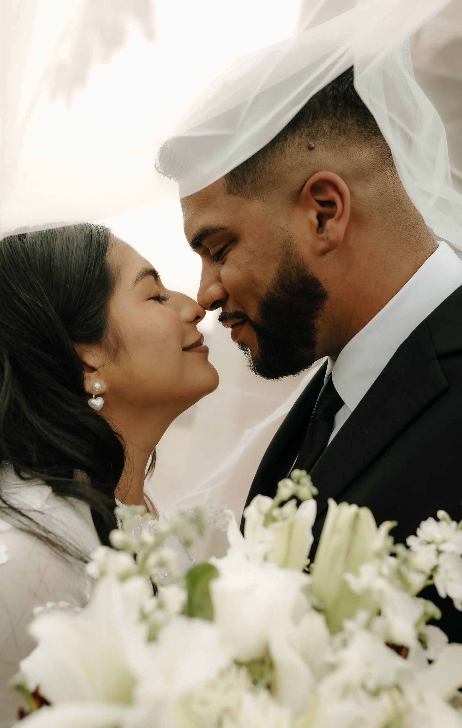 Romantic wedding portrait with white flowers in foreground.