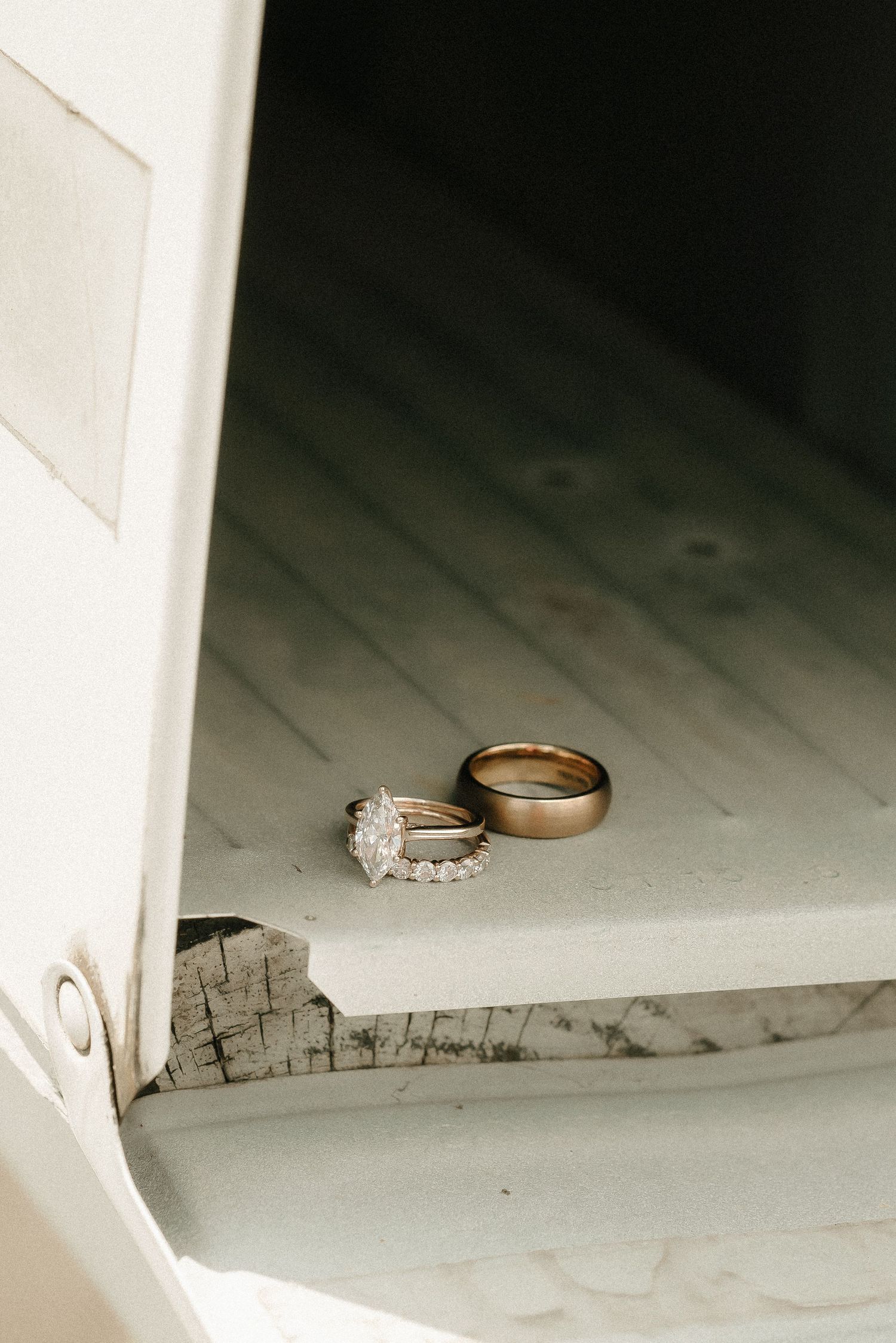 Wedding rings displayed on a white surface in dramatic lighting.