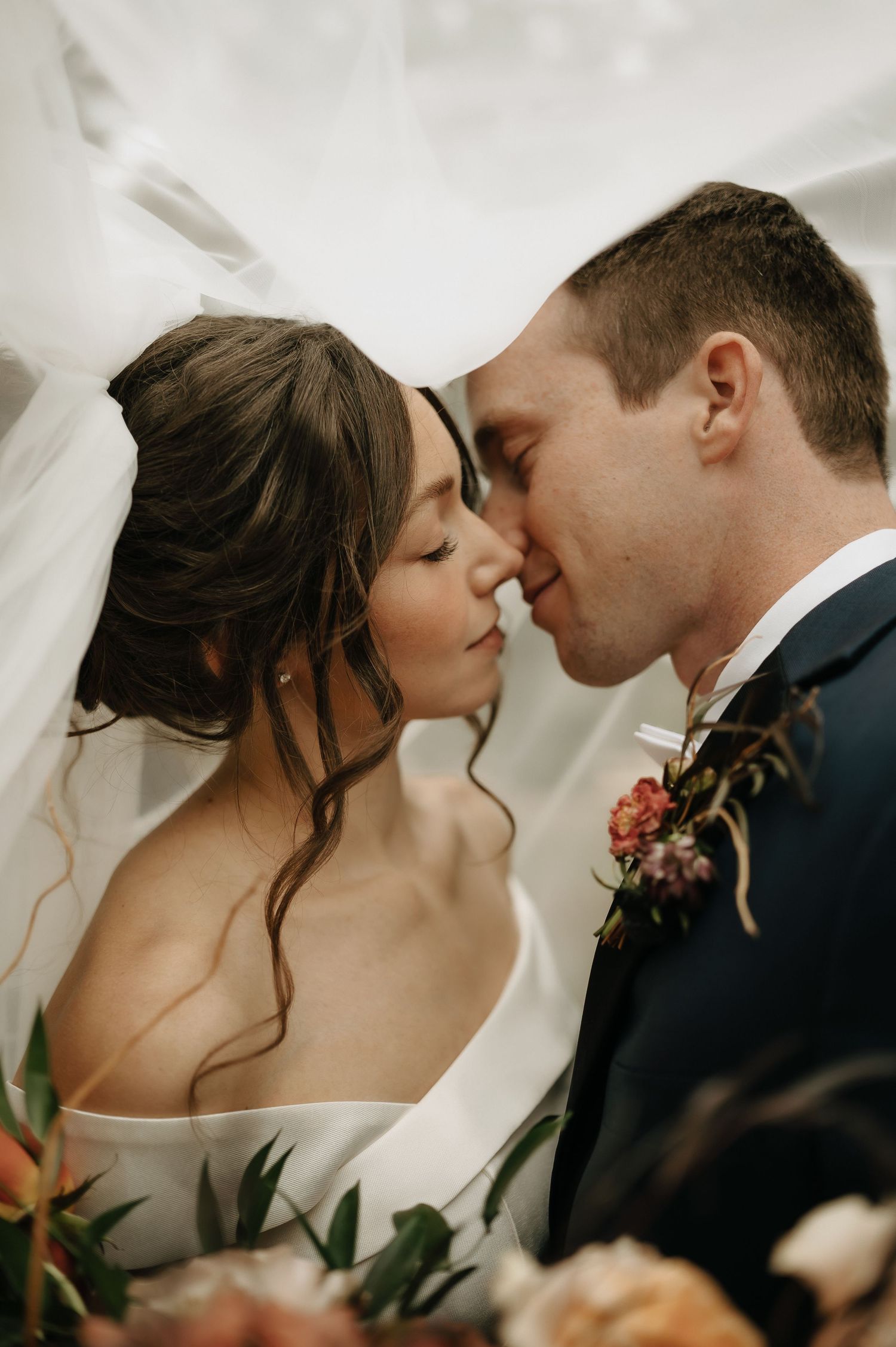 Intimate romantic wedding portrait with delicate florals and soft lighting.