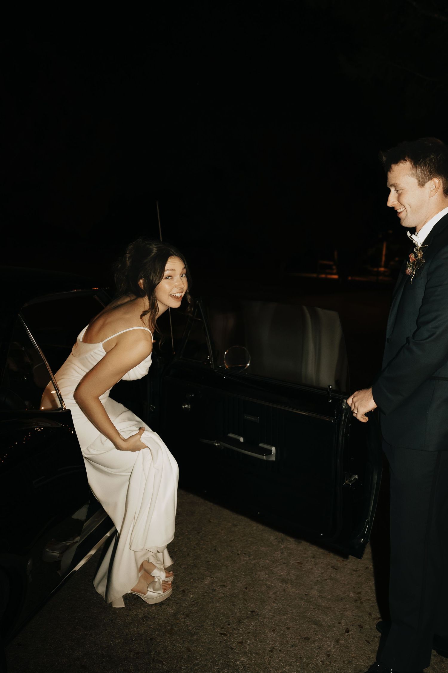 Couple performing dance moves in formal wedding attire during an evening reception.