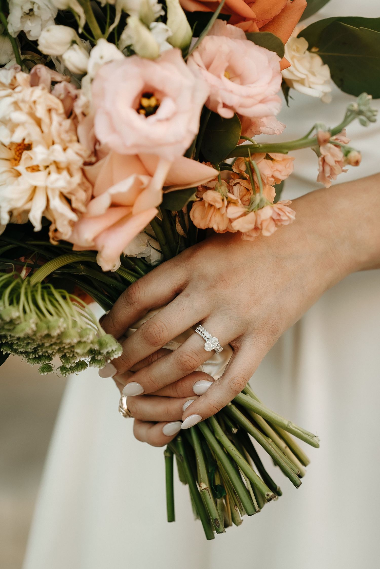 Close-up of engagement ring with blush pink wedding bouquet.