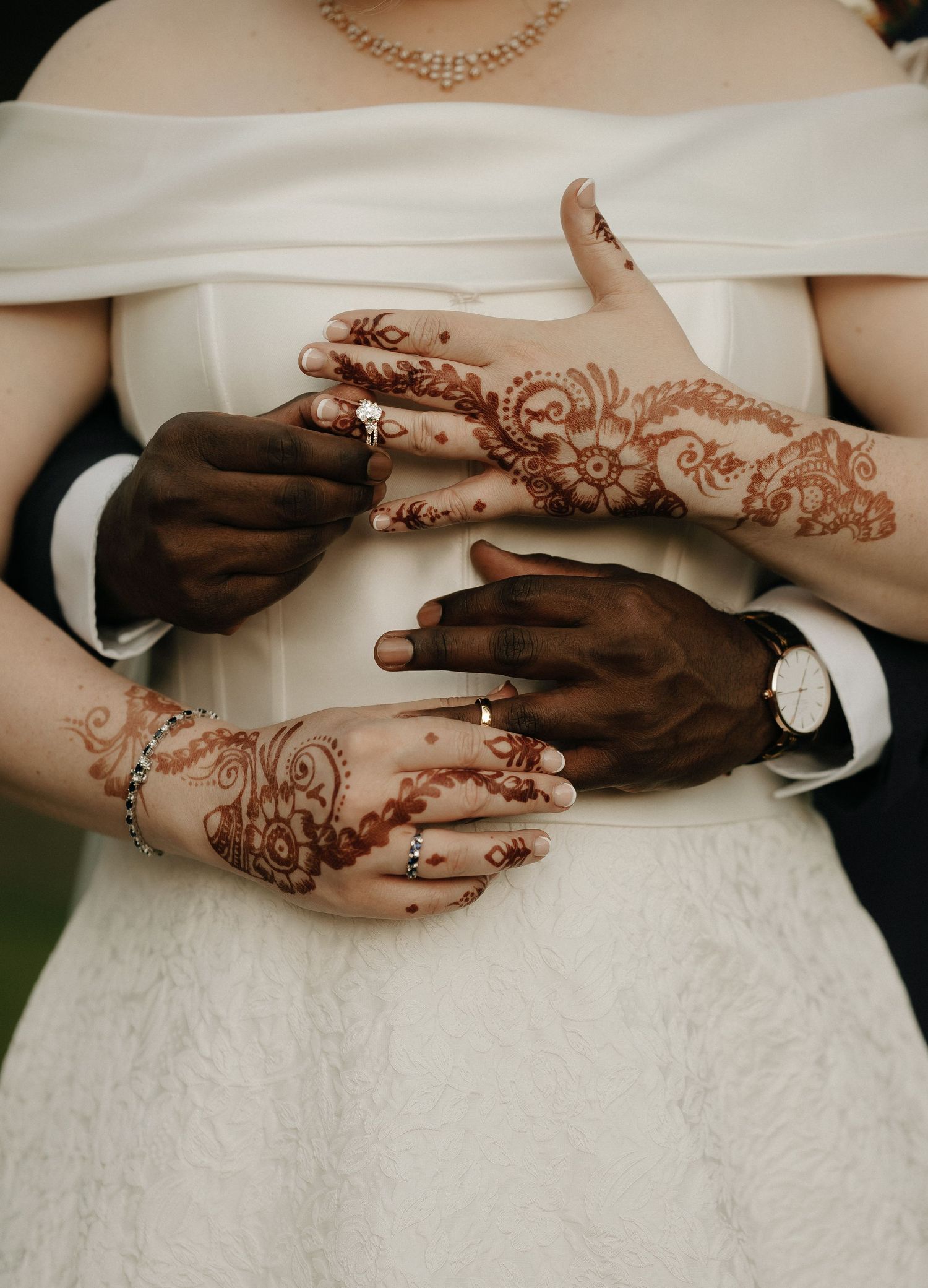 Detailed shots of hands with henna designs against white wedding dress.