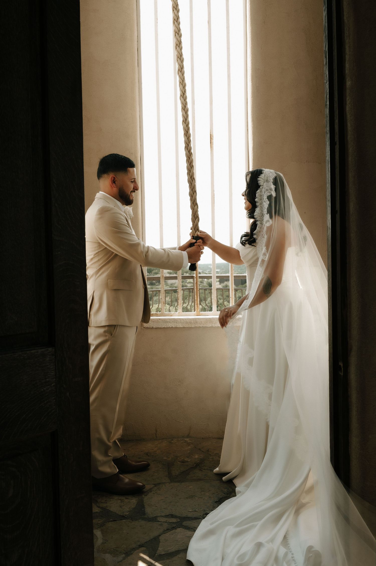 Romantic wedding moment captured by a window with natural light streaming in.