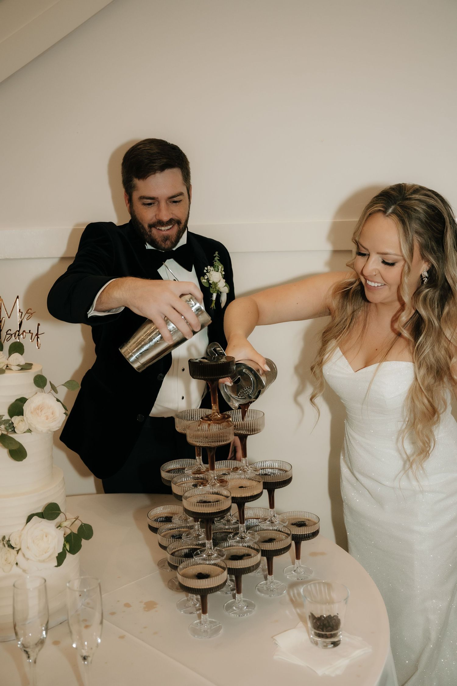 A champagne tower being filled at an elegant wedding reception celebration.