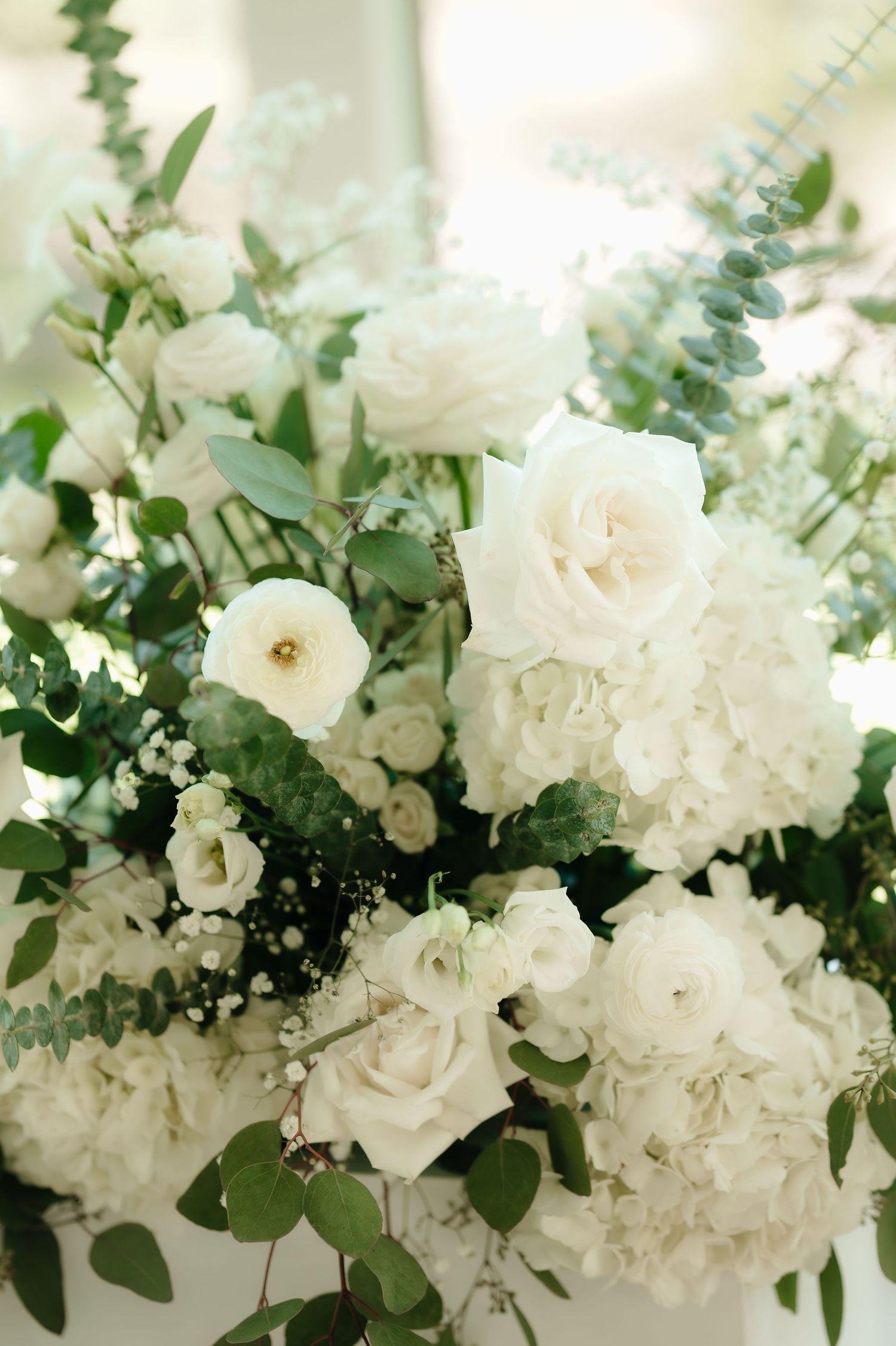 Luxurious white floral arrangements with roses and greenery for wedding decor.