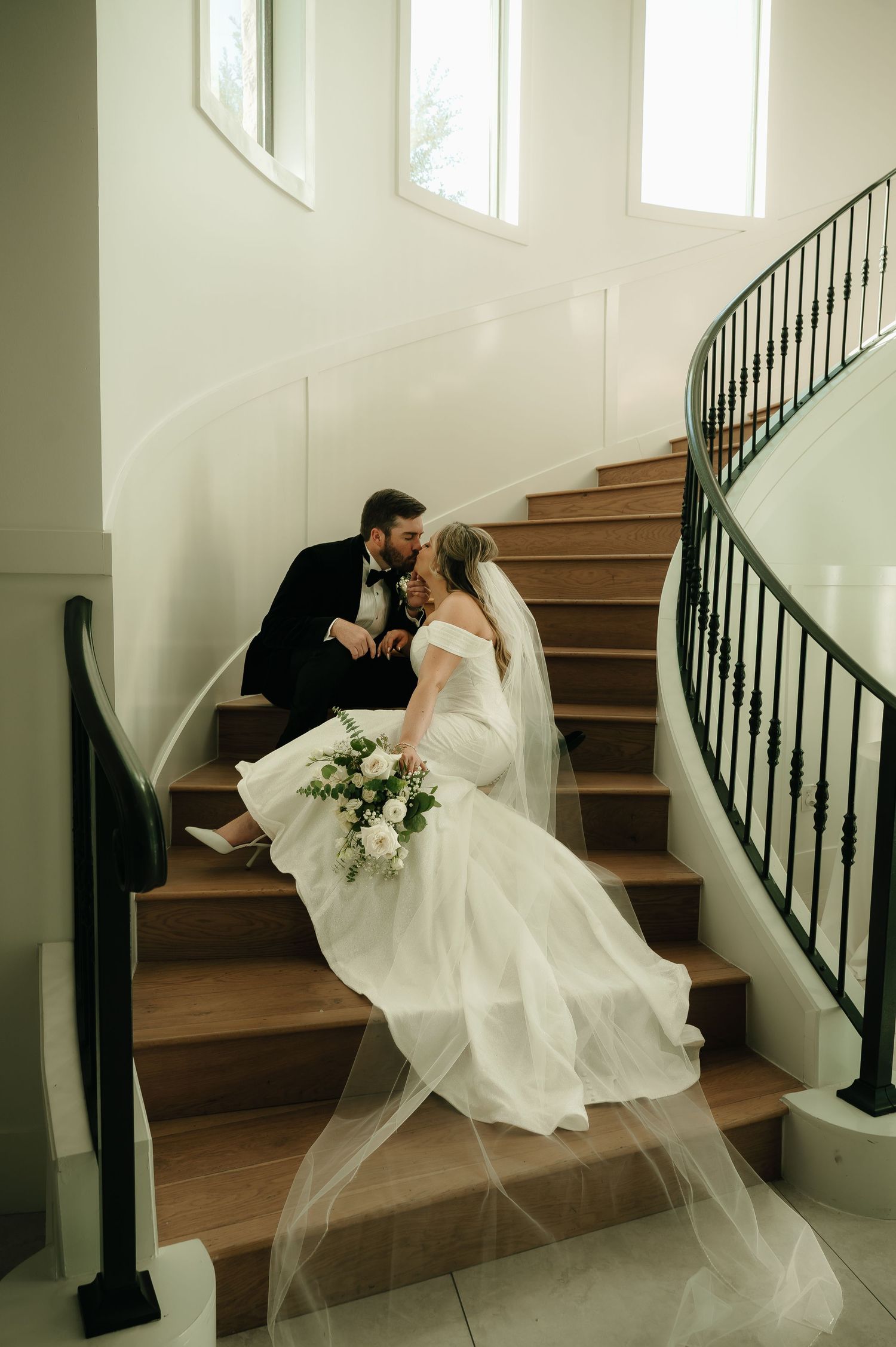 A romantic wedding photo series showing a couple posing on elegant wooden stairs with a black railing.