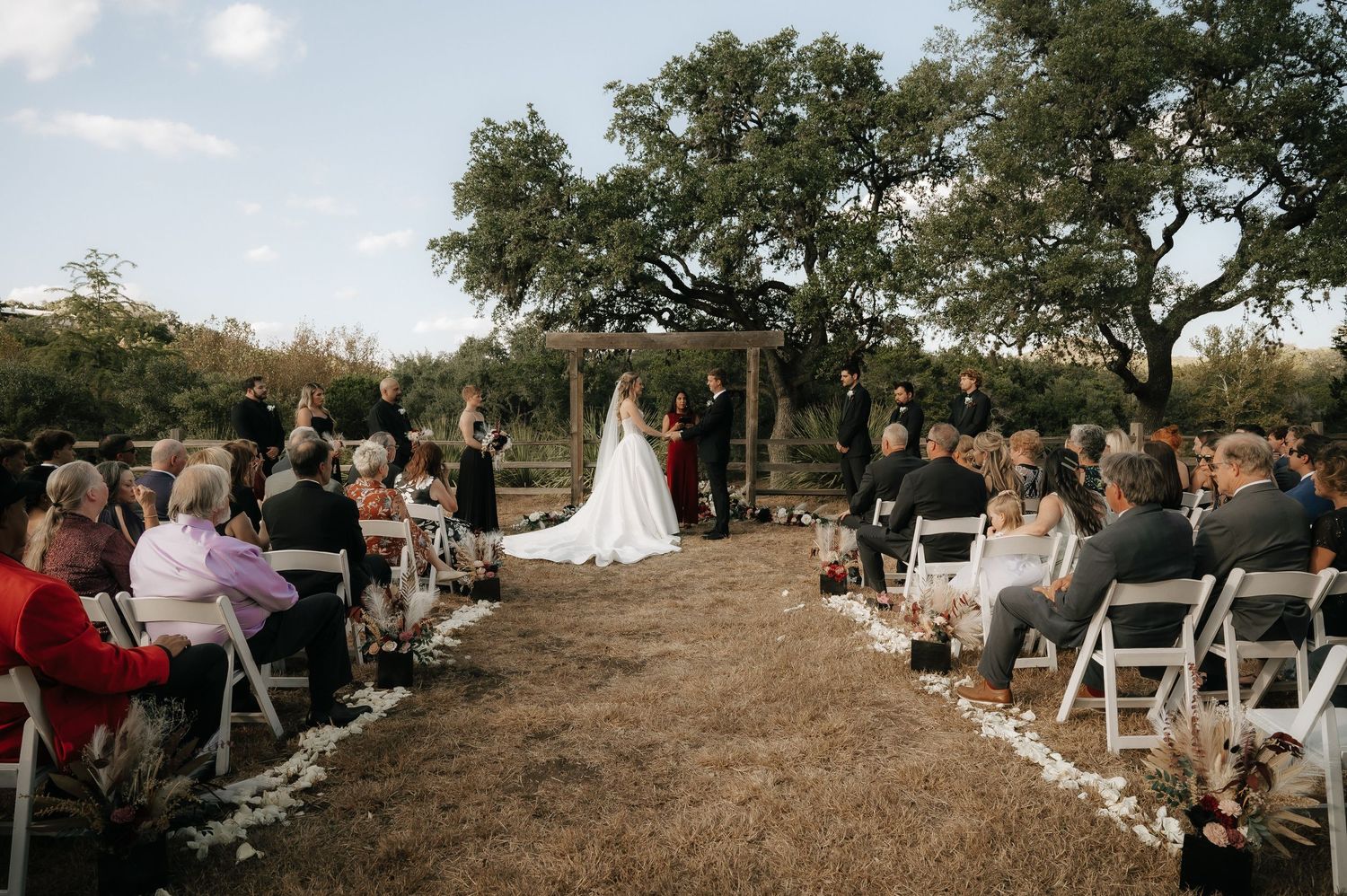 Panoramic view of outdoor wedding ceremony setup with white chairs and natural landscape.
