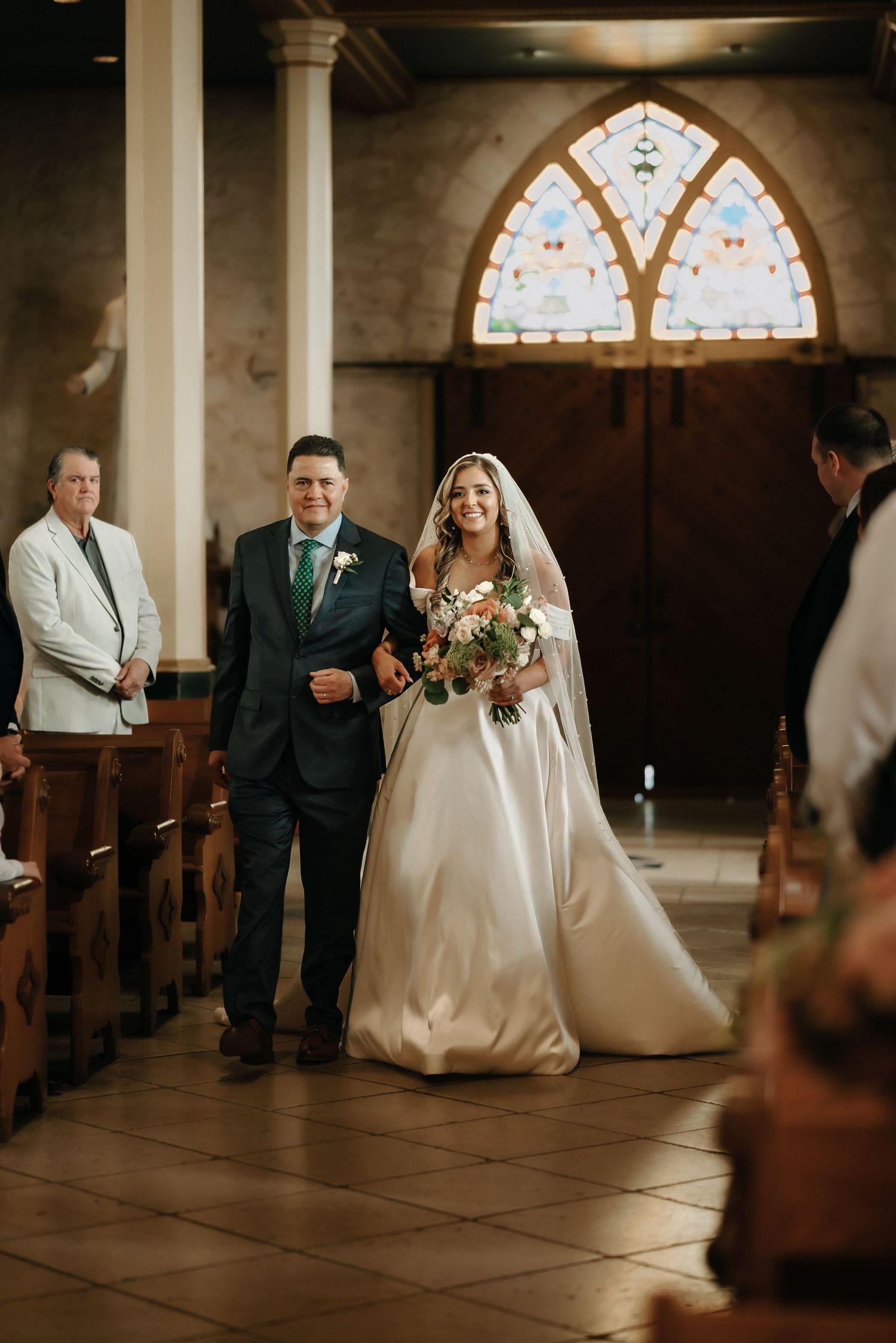 Wedding ceremony in a historic church with stained glass windows and stone architecture.
