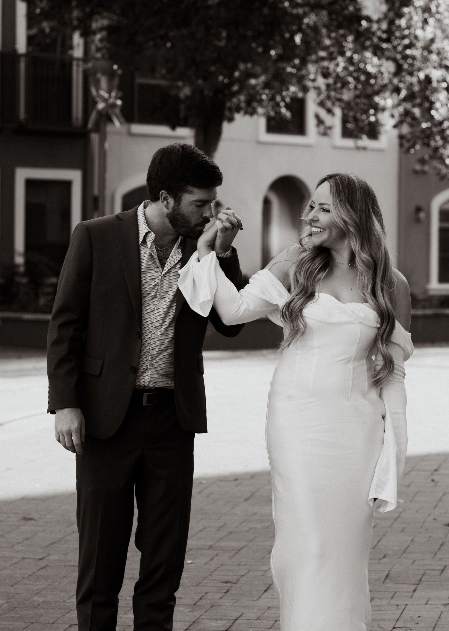 Black and white photo of couple walking together on brick pavement.