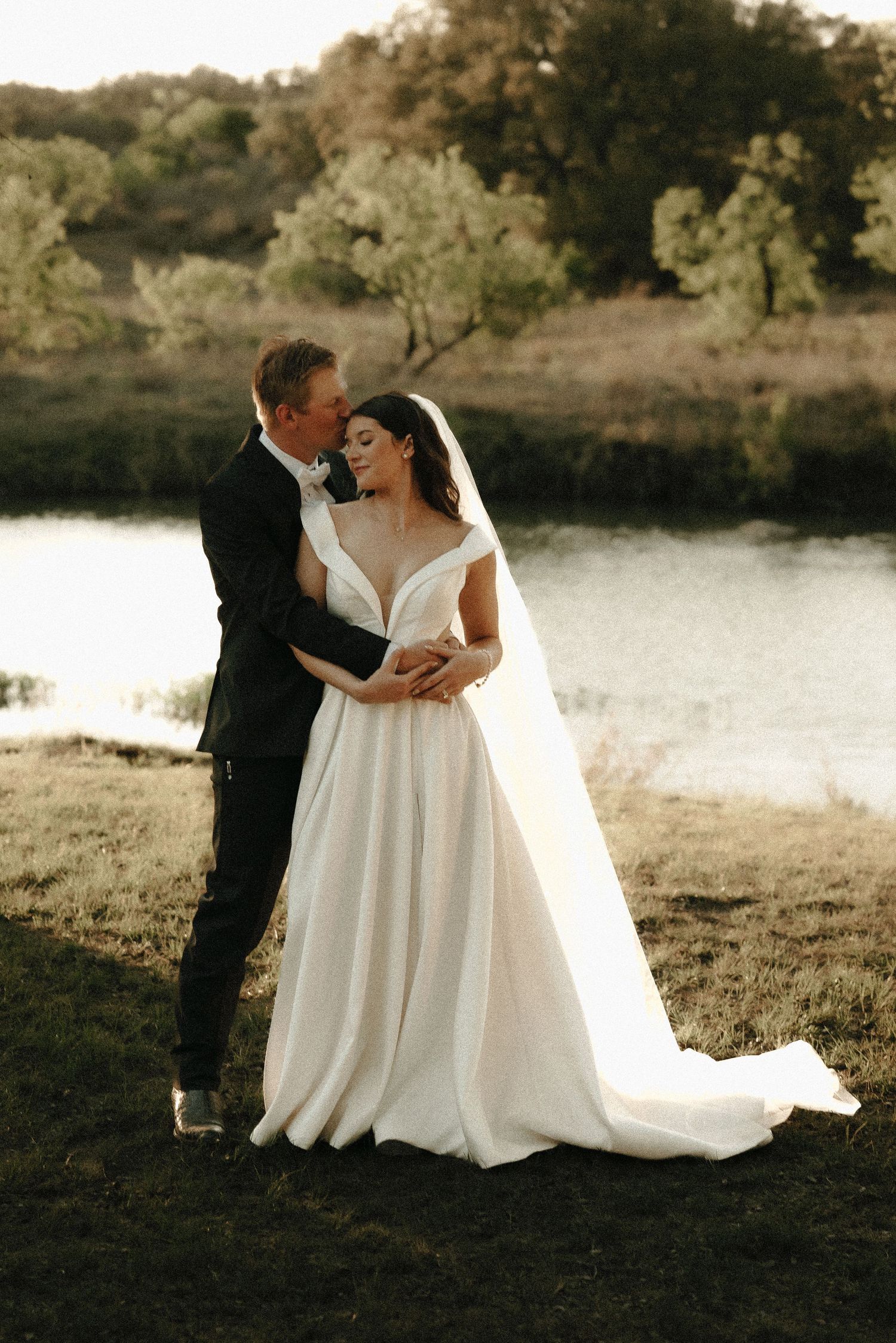 Romantic waterfront wedding portraits at sunset with flowing white dress.