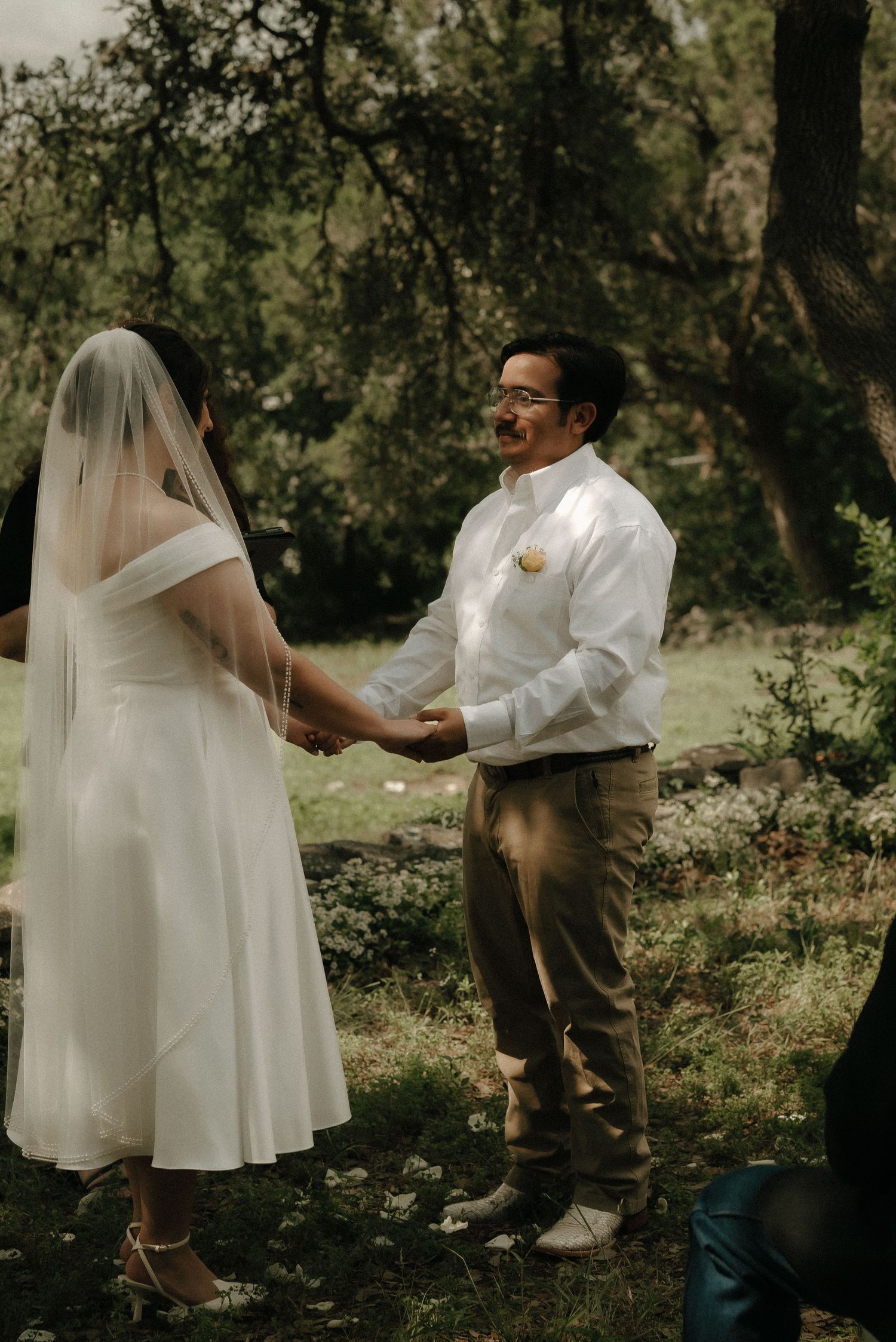 A couple exchanges vows during their outdoor wedding ceremony surrounded by trees.
