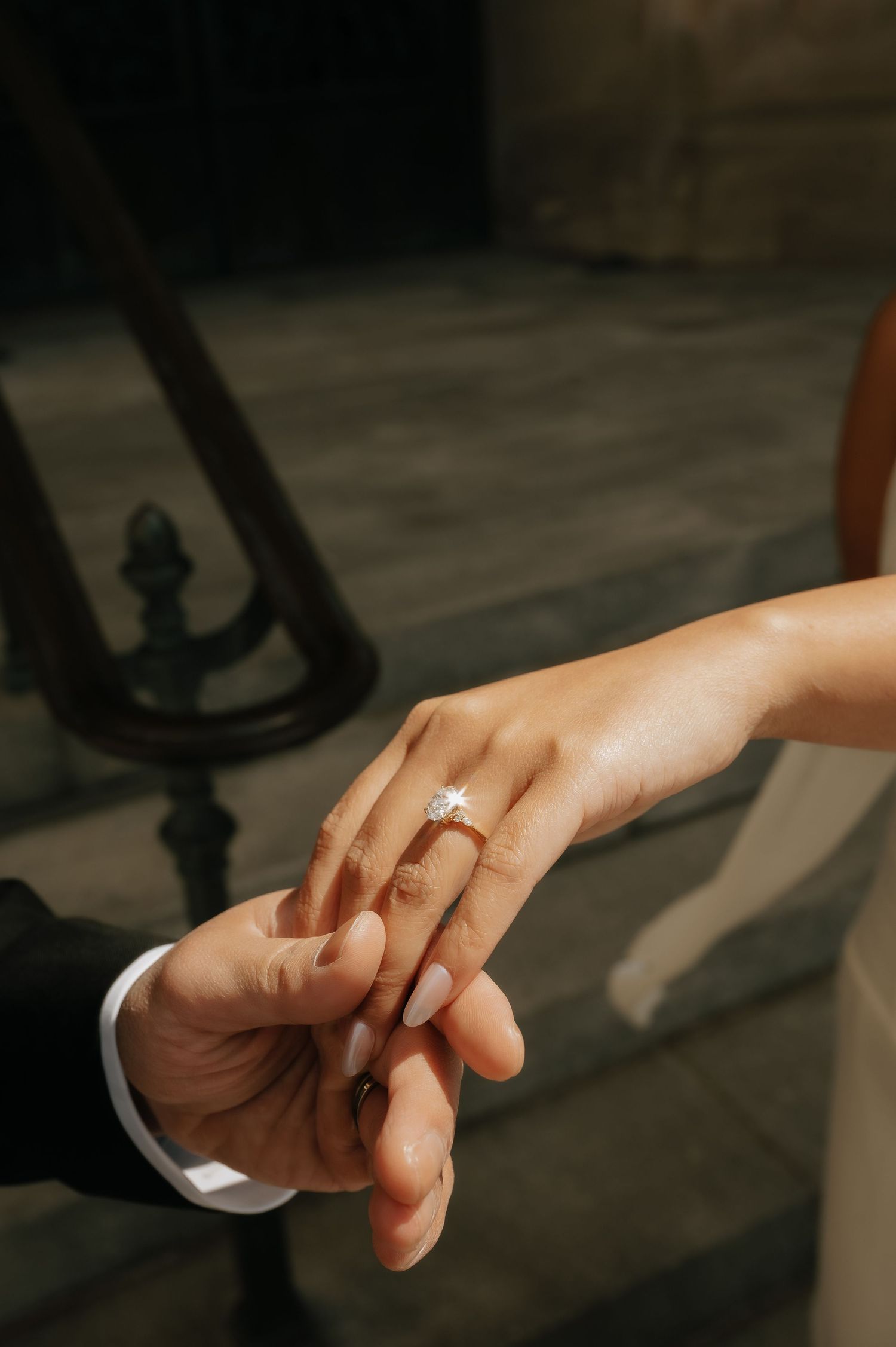 Close-up of a couple holding hands with a stunning diamond engagement ring on the bride's finger.