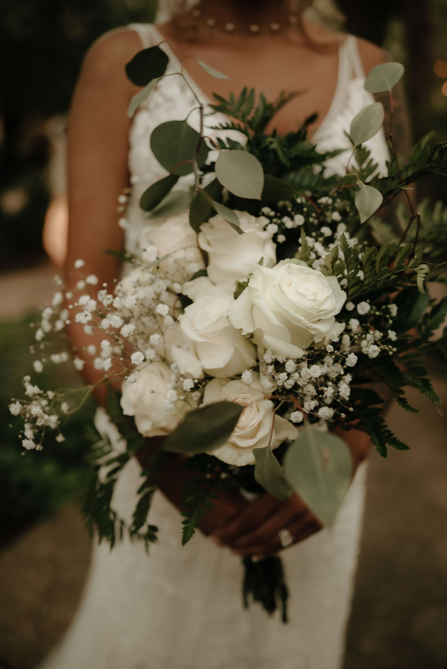 Elegant white bridal bouquet with roses, baby's breath, and eucalyptus leaves.