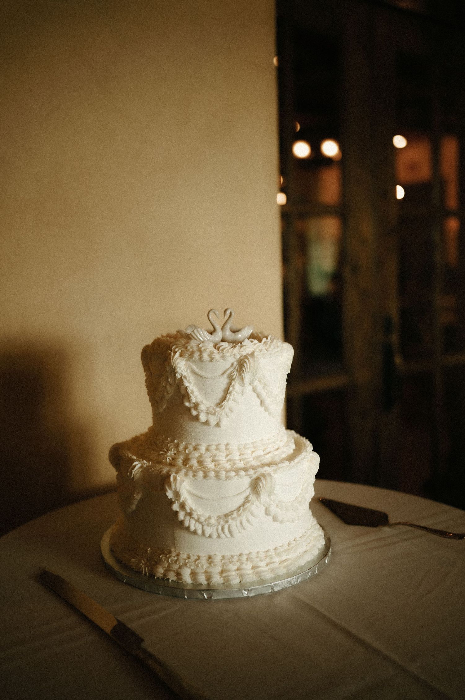 An elegant two-tier white wedding cake with delicate piped details and a decorative topper.