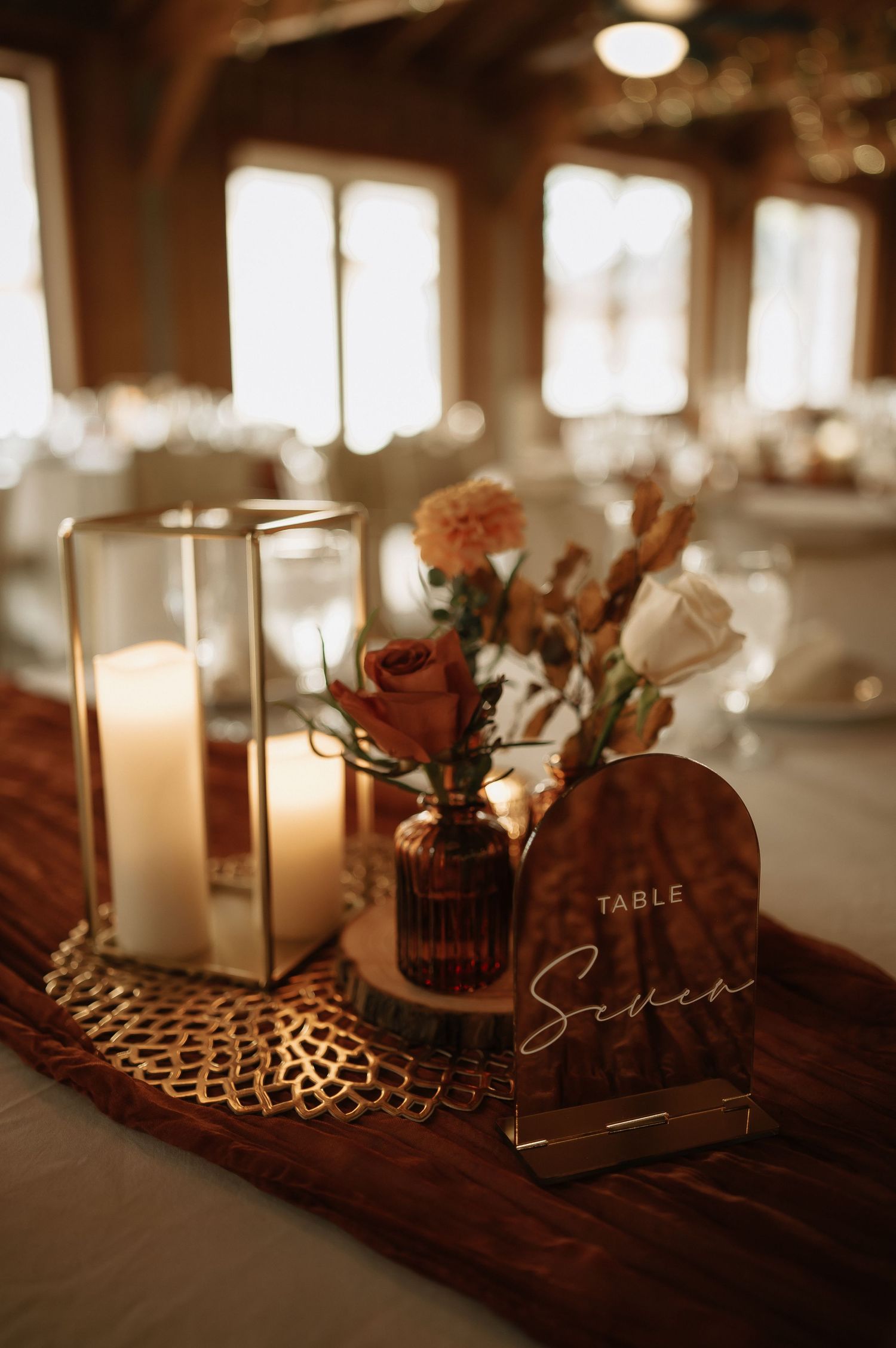 Romantic table setting with candles and floral centerpieces in warm ambient lighting.