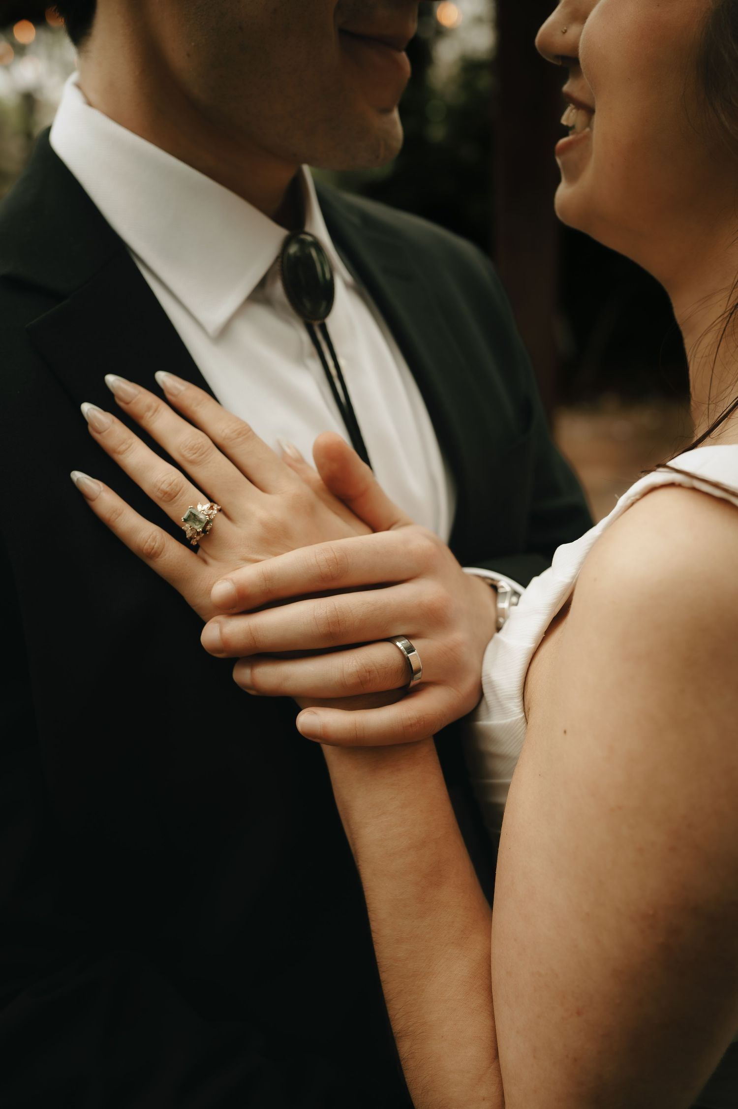 Close-up of hands with engagement ring as couple shares tender moment.