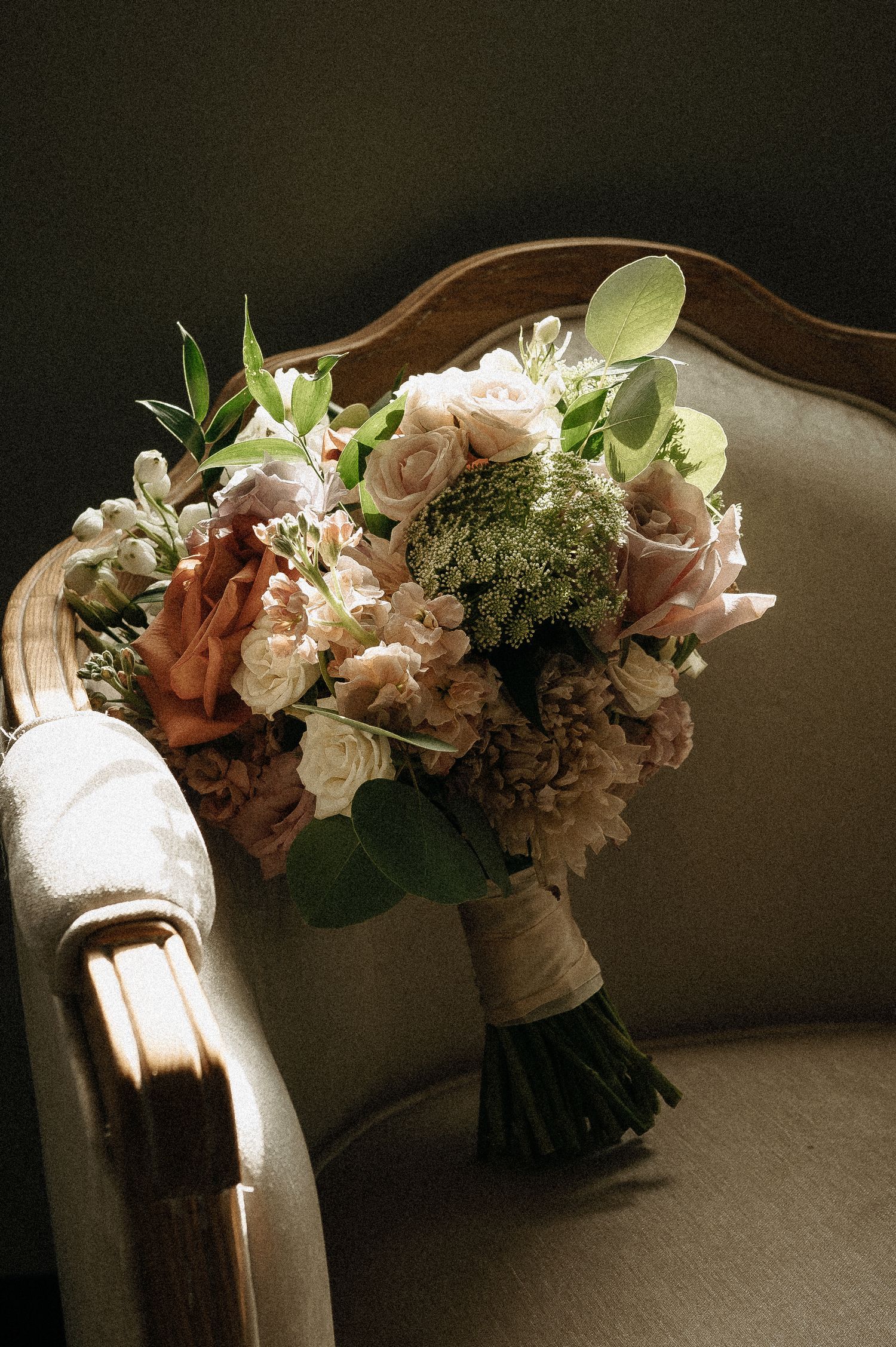 Elegant floral bouquets lined up on a vintage settee in soft natural light.