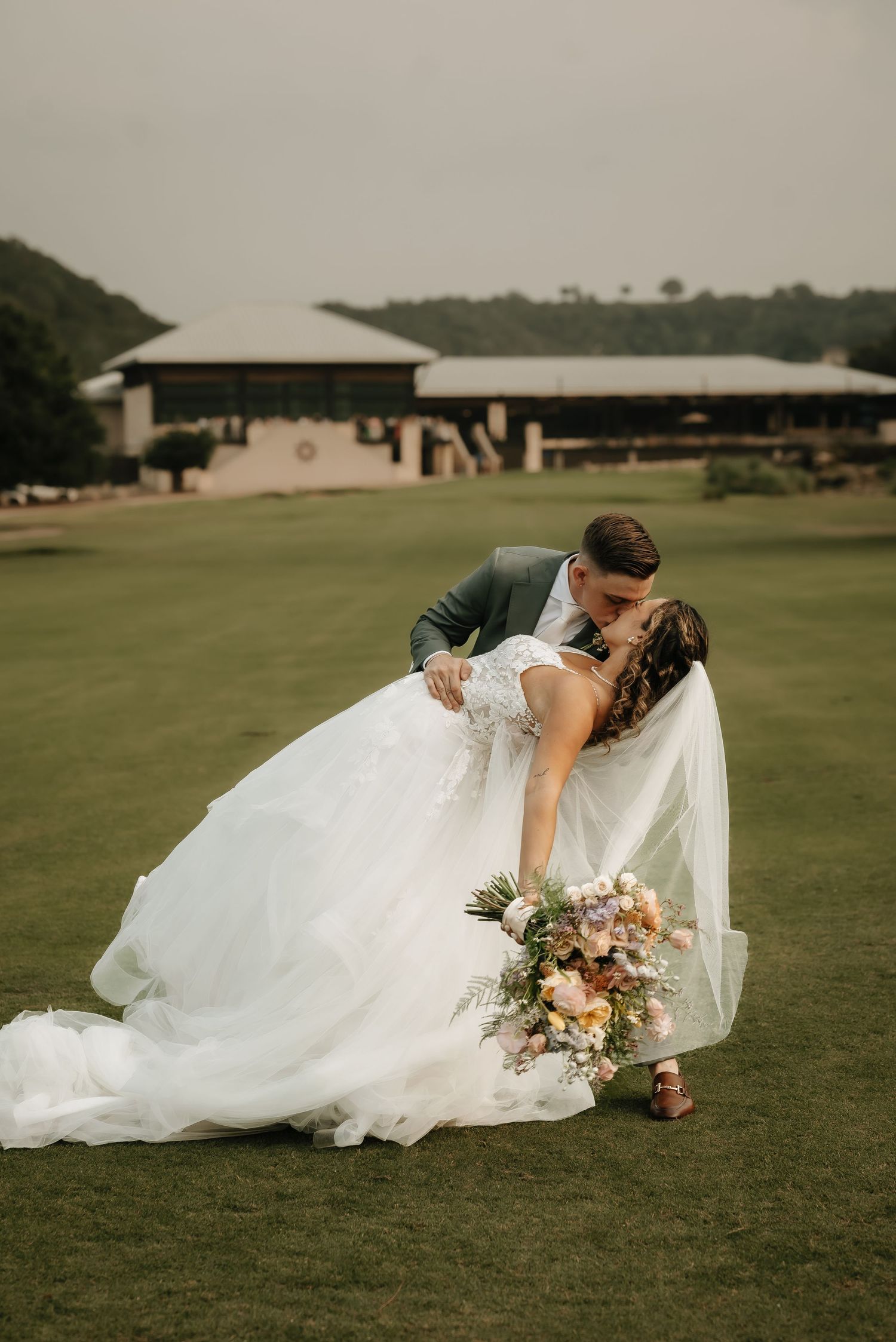 A romantic wedding photo series showing a couple lying on lush green grass with flowing white dress details.