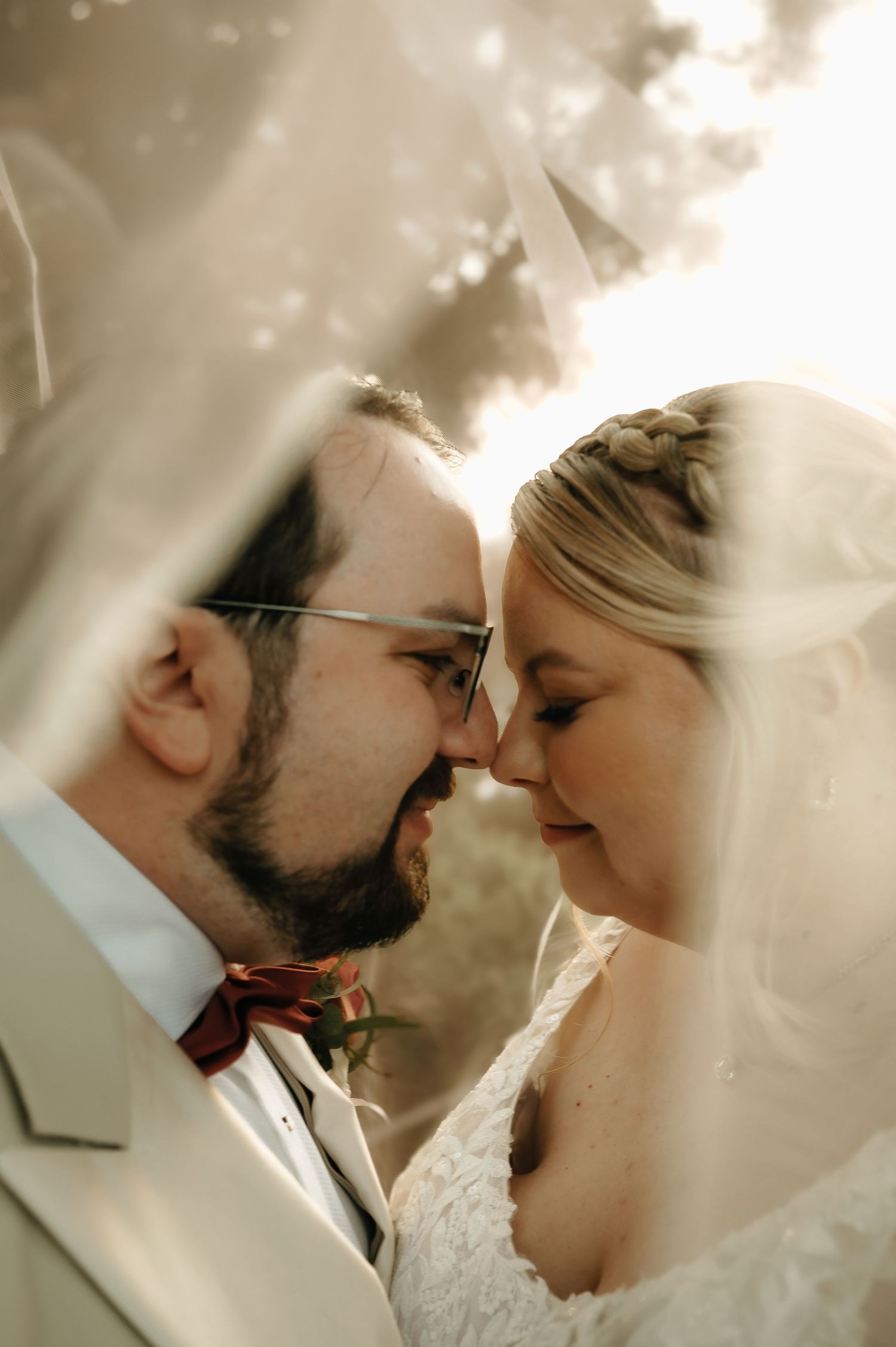 Intimate wedding portrait captured through delicate veil during romantic moment.