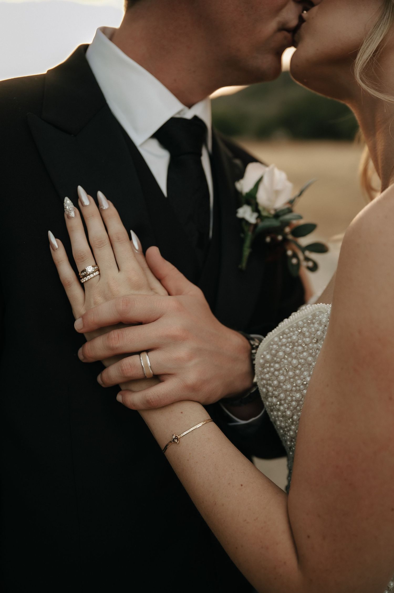 Close-up of wedding rings and hands during intimate moment between newlyweds.