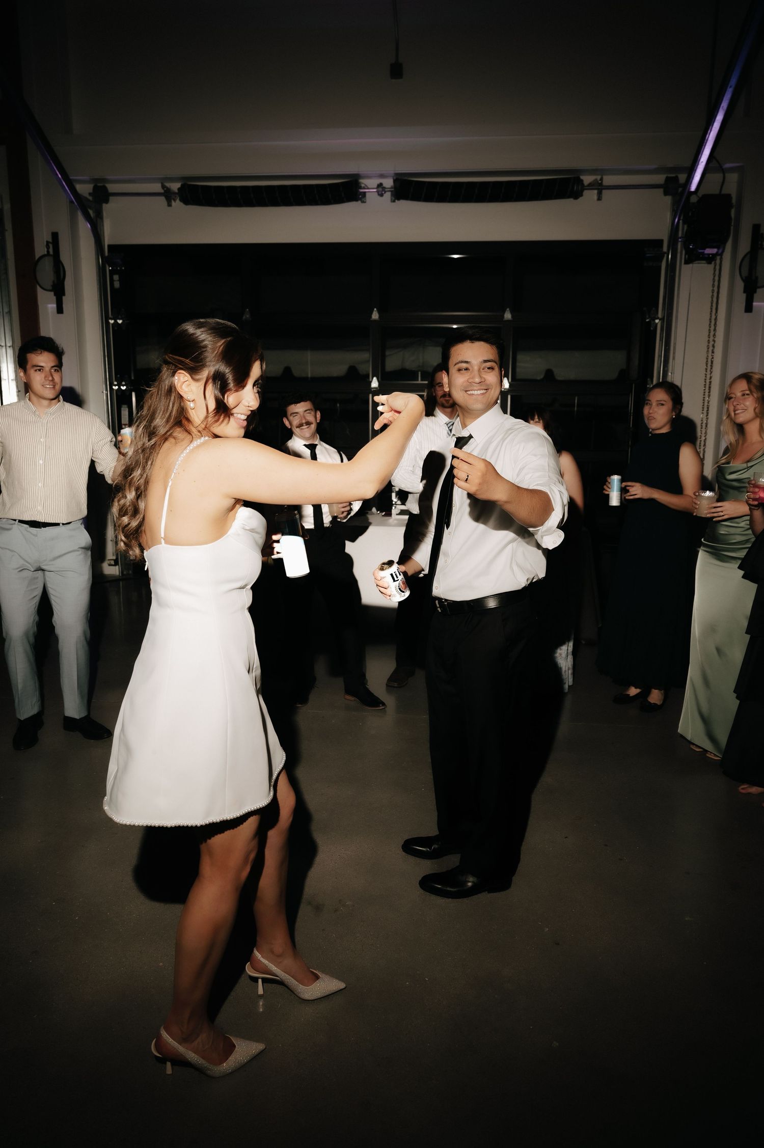 Bride and groom dancing joyfully on the dance floor surrounded by guests at their wedding reception.