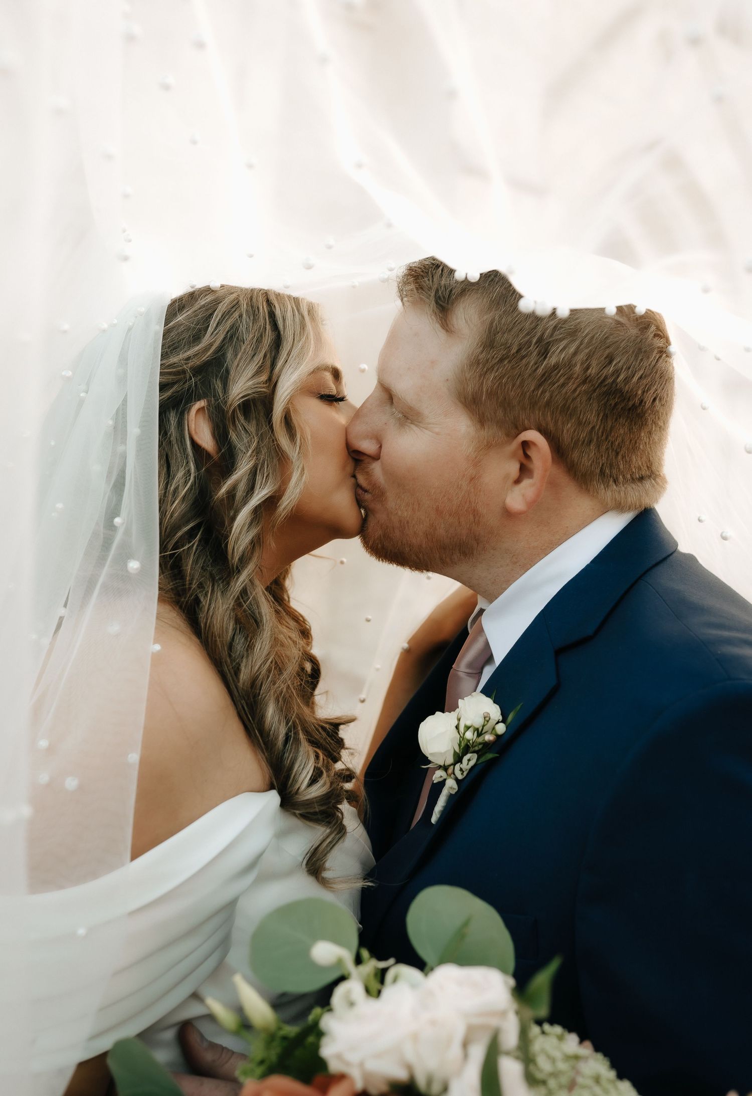 Intimate wedding moment captured through delicate veil.
