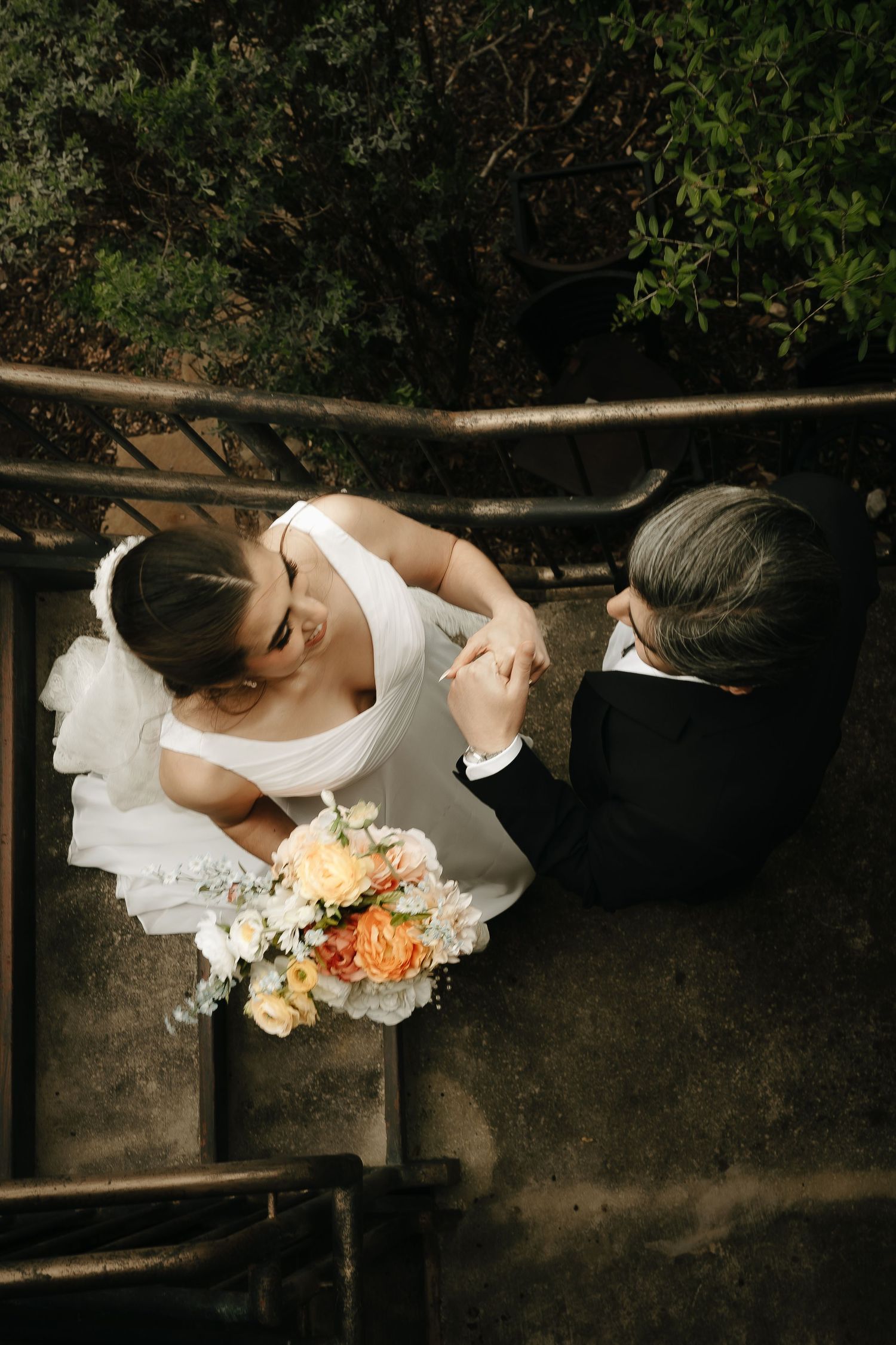 Artistic overhead shot of a bride's dress and bouquet with peach and white flowers.