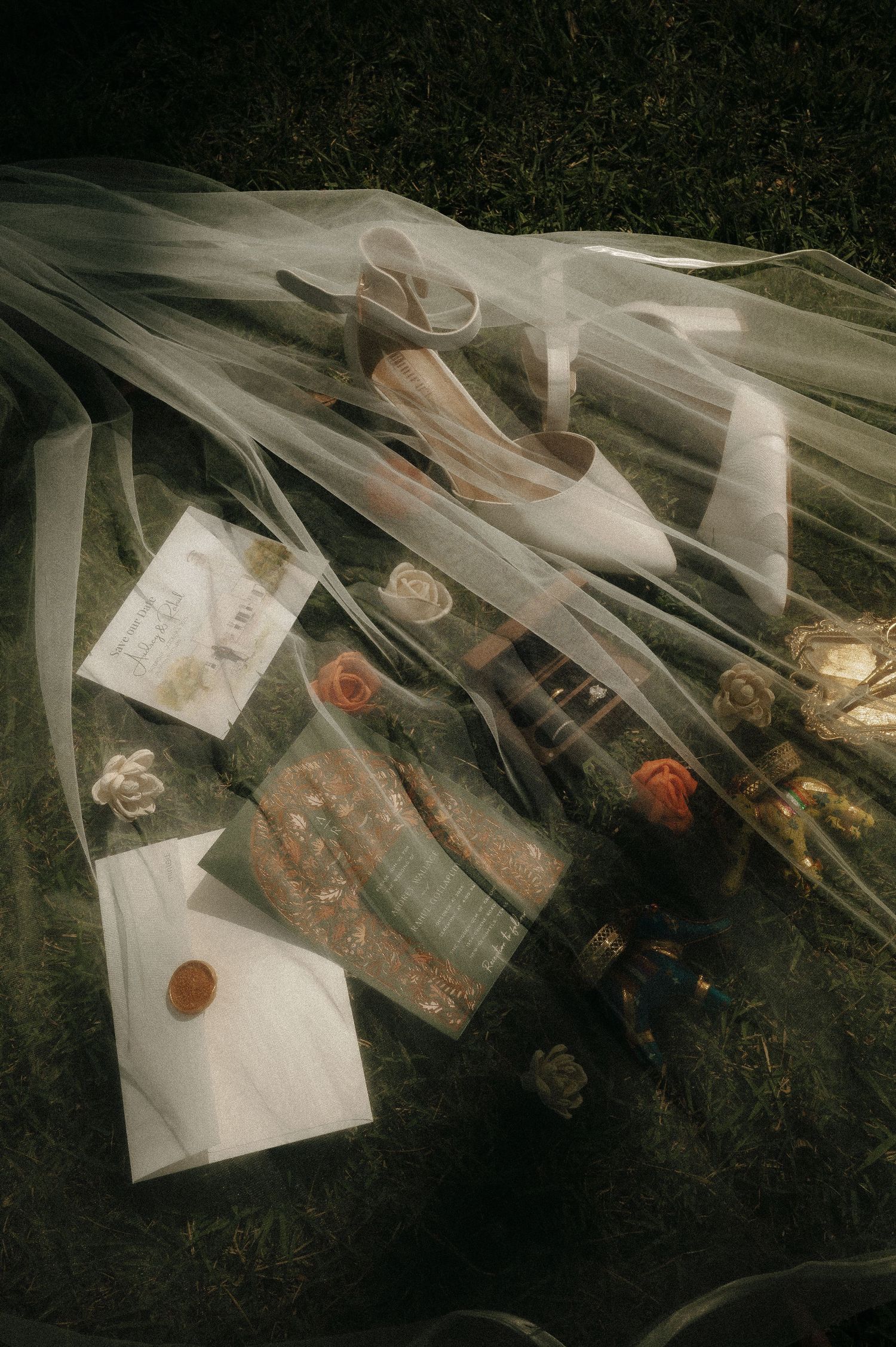 Wedding details artistically arranged under flowing veil including letters and mementos.