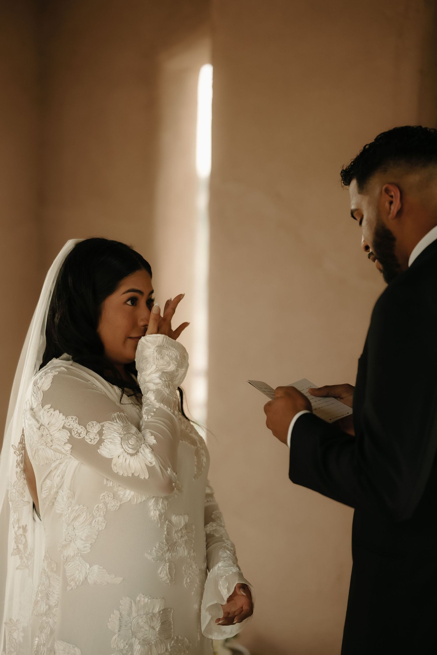 Intimate wedding sequence showing couple in white dress and dark suit reading vows in natural light.
