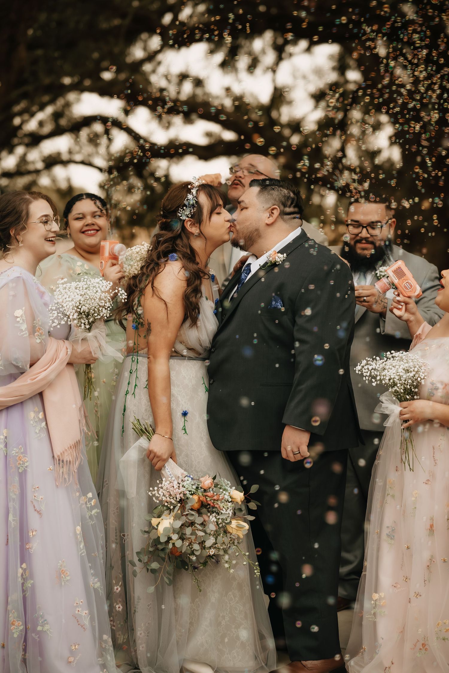 Wedding party celebrating with confetti and laughter in soft pastel attire.