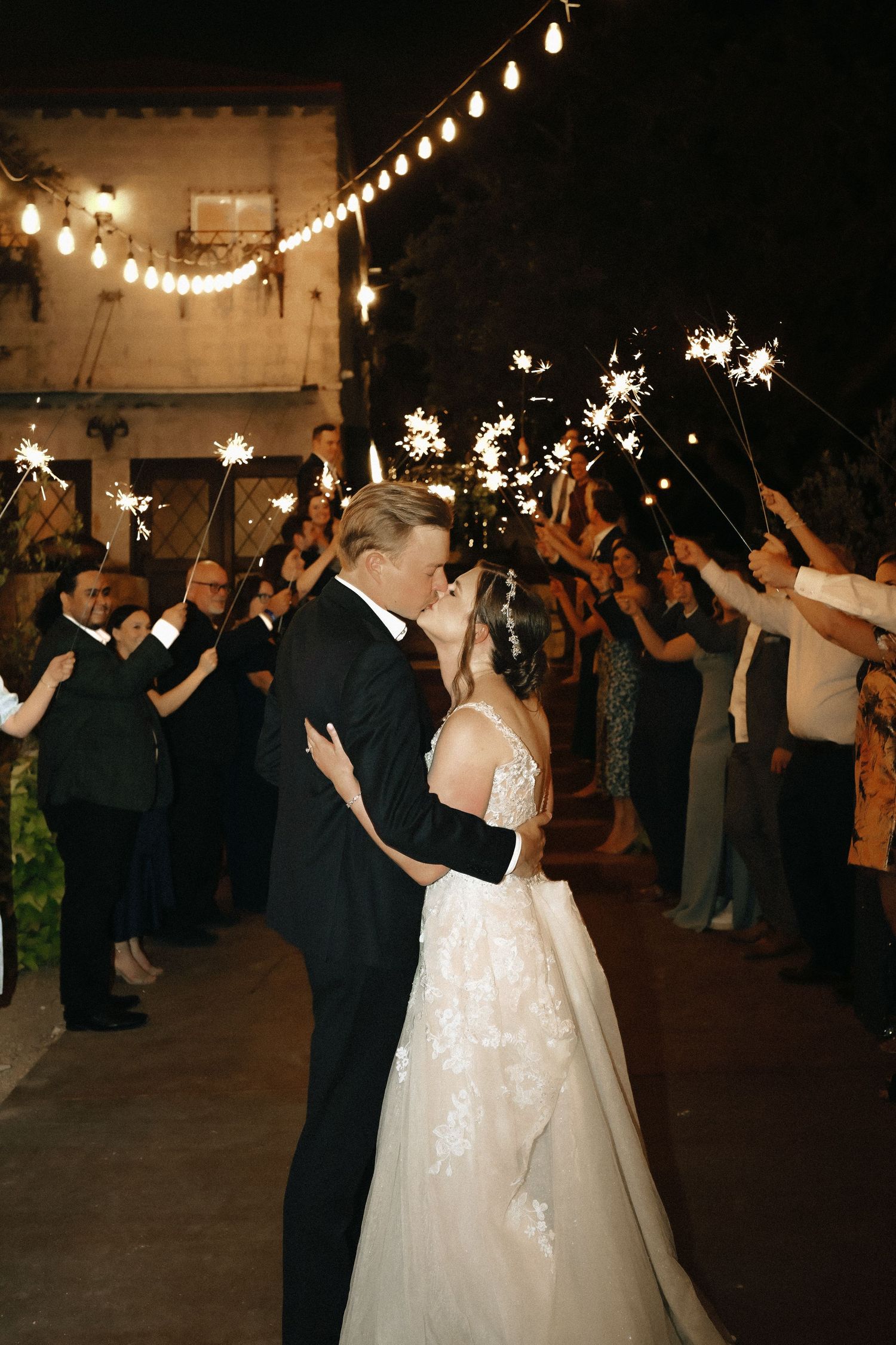 Wedding celebration at night with sparklers creating magical light around dancing couple.