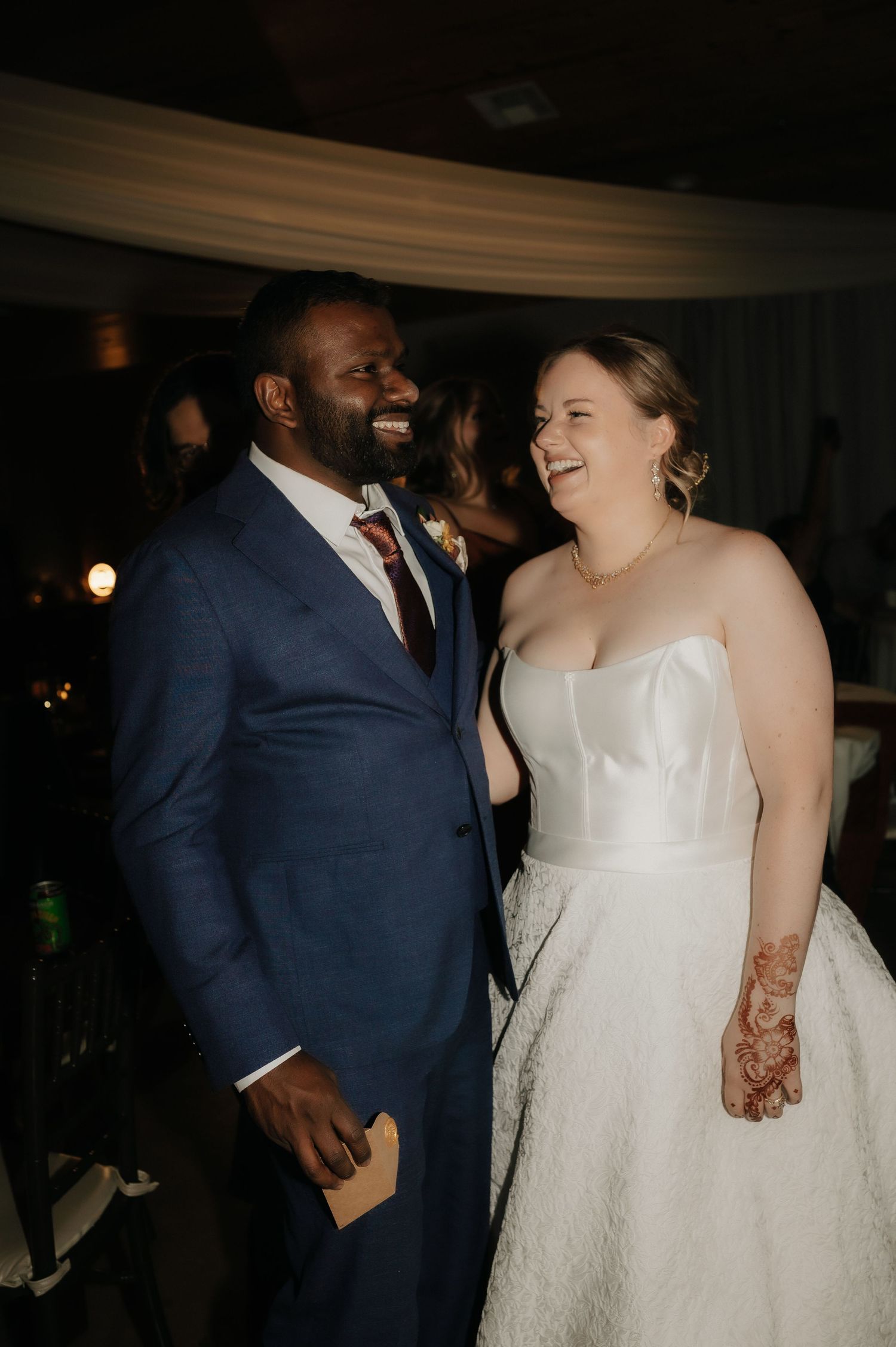 Happy couple sharing joyful moment during indoor wedding reception.