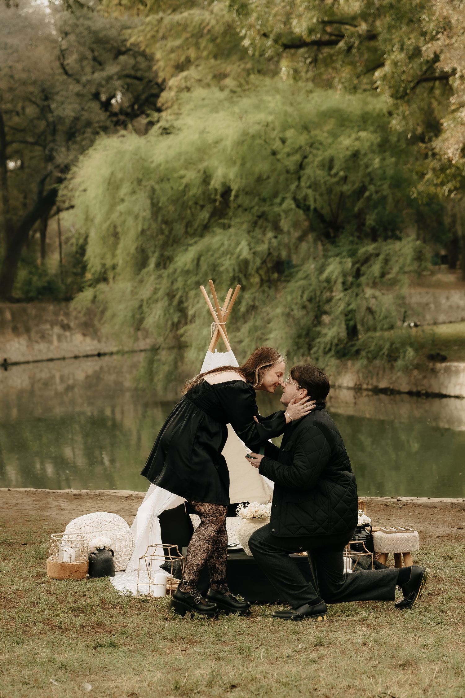 Couple enjoying romantic moments during lakeside picnic engagement session.
