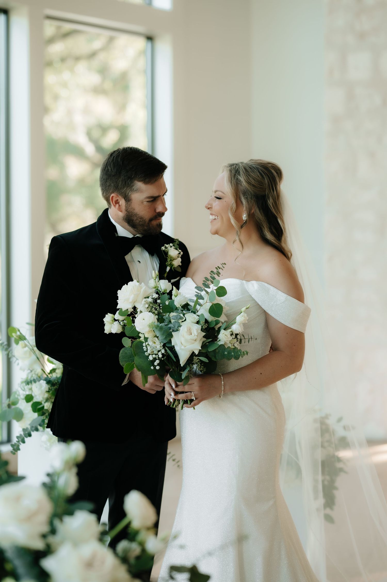 Bright indoor wedding photos with white floral arrangements and natural window light.