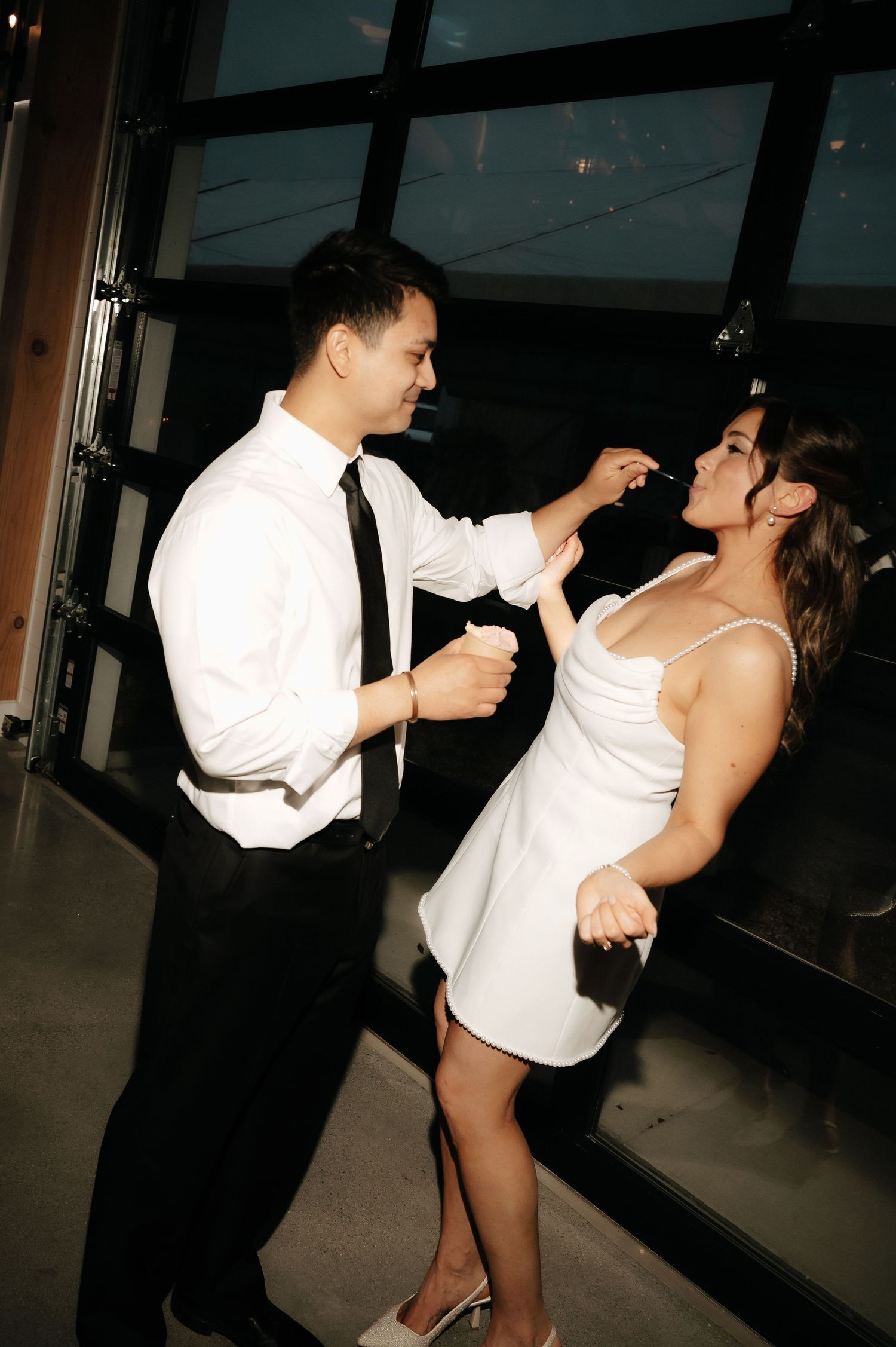 Couple dancing elegantly in white dress and black tie attire at a formal evening event.