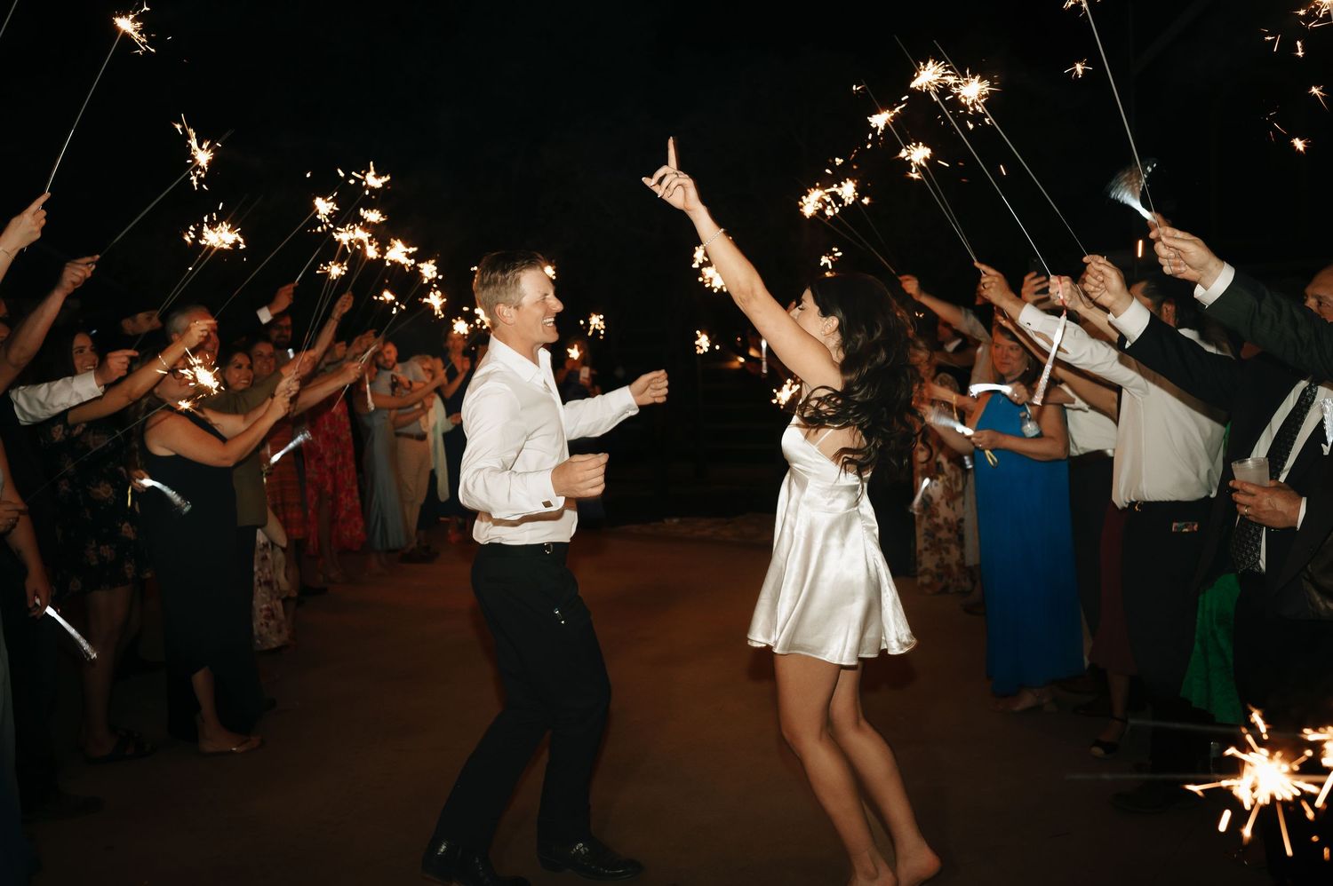 Wedding celebration at night with sparklers creating magical light trails on the dance floor.