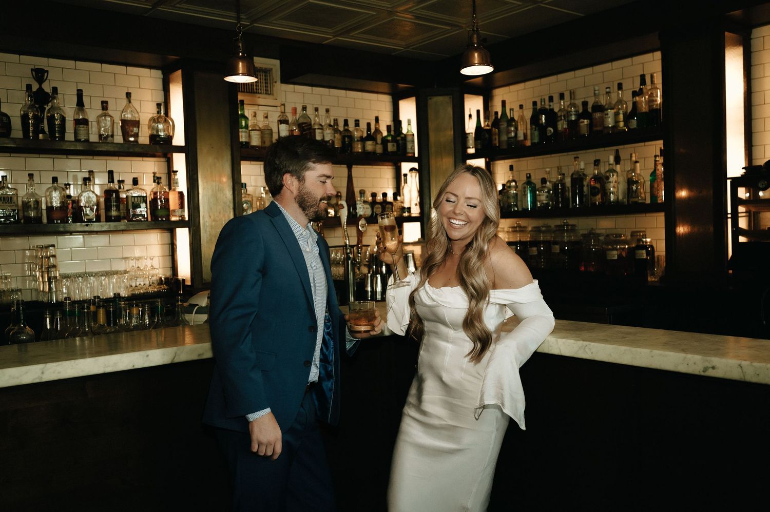 Stylish couple in formal attire sharing a moment at an upscale bar.