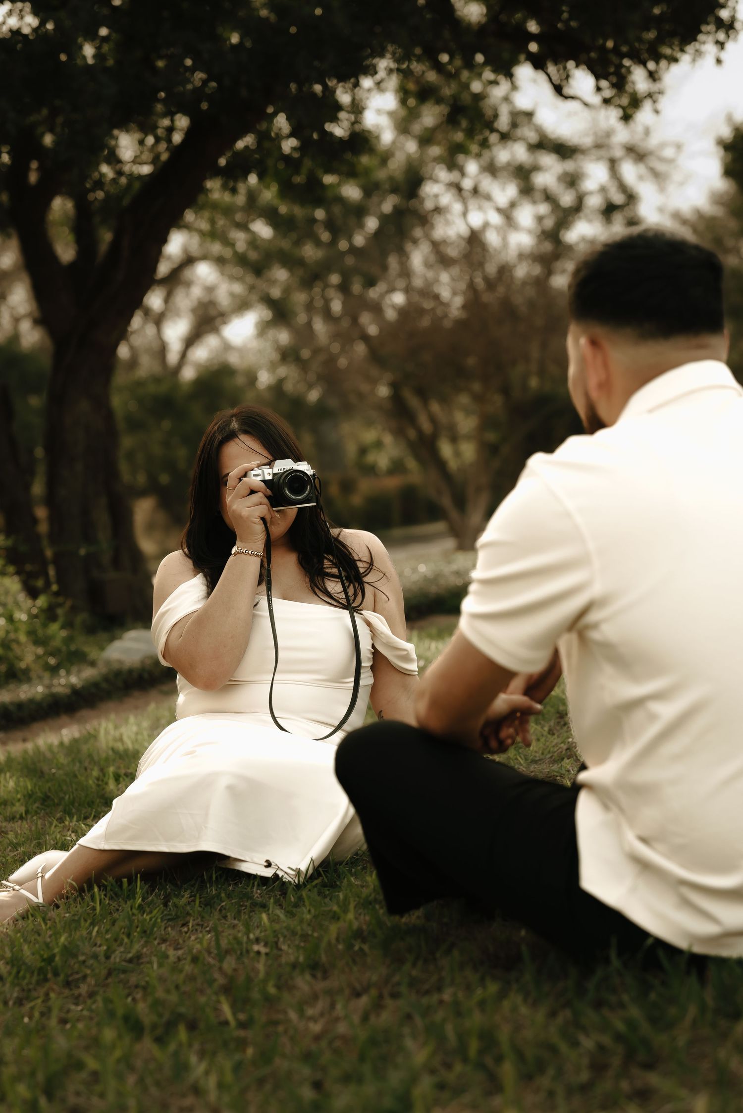 A couple lying on grass having a casual photo session outdoors.