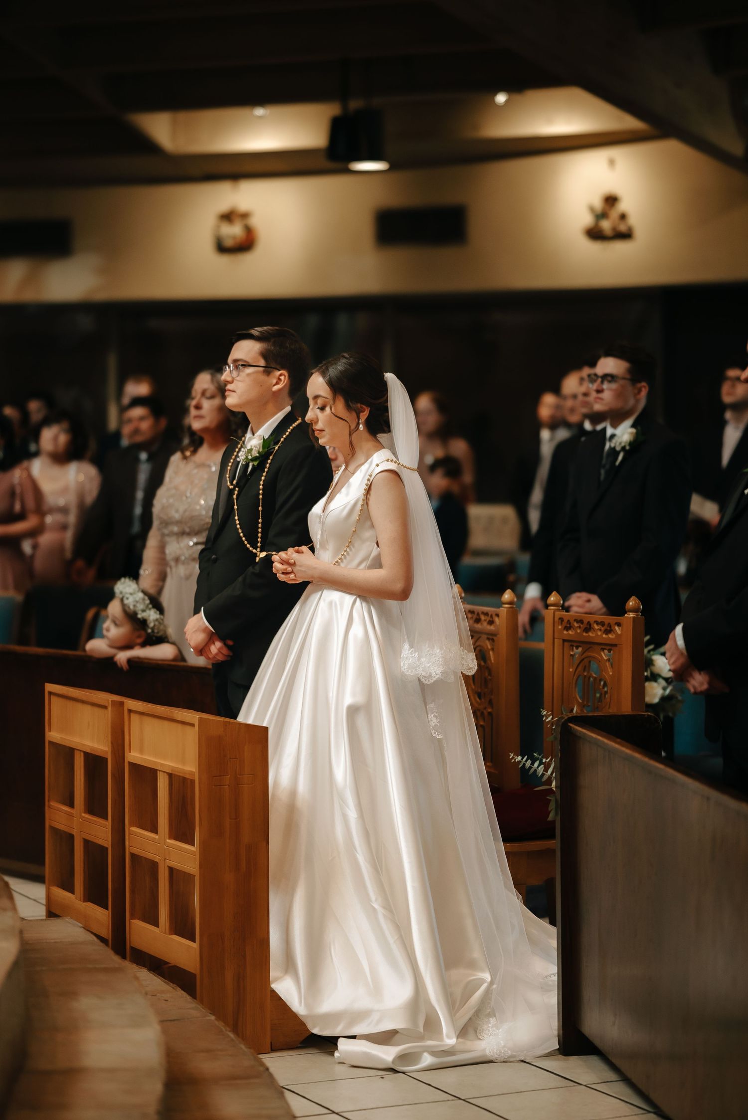 Wedding ceremony in a traditional church with couple standing at wooden pews during the service.