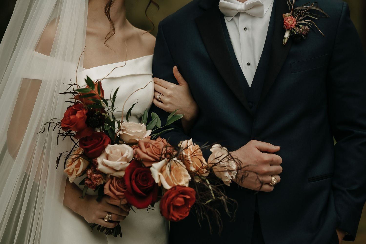 Detail shot of wedding attire with autumn-colored flowers and formal wear.