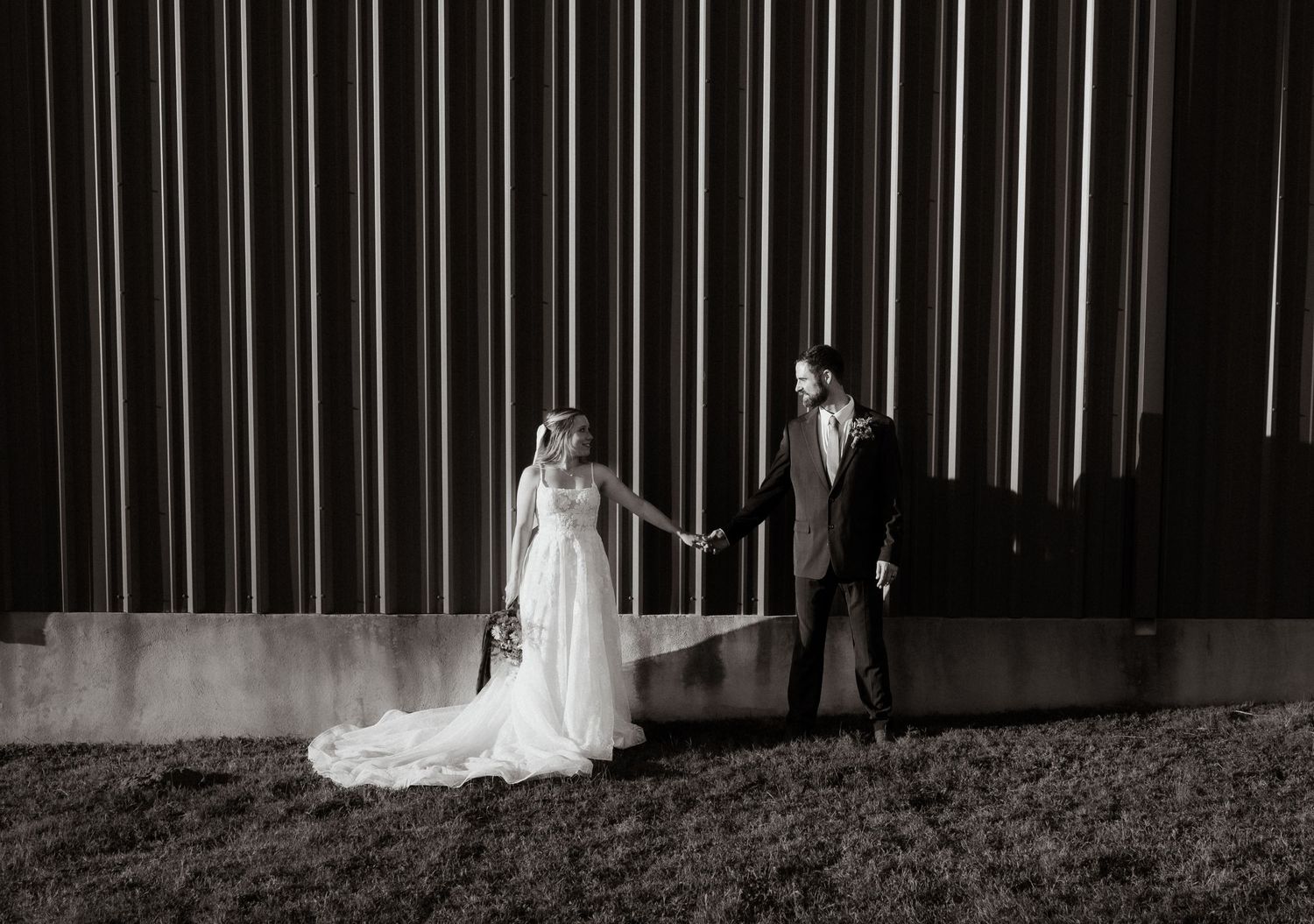 Artistic black and white silhouette of wedding couple against vertical lined backdrop.