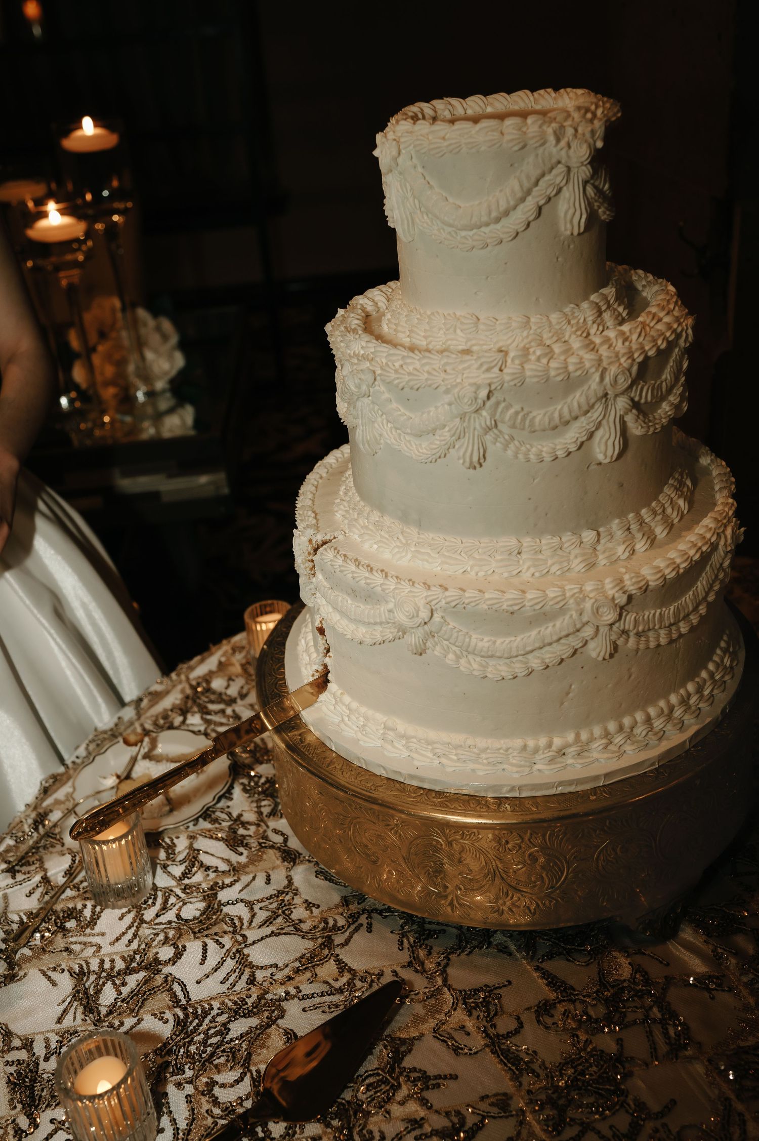 Elegant white wedding cake with intricate piping details on a lace-covered table.