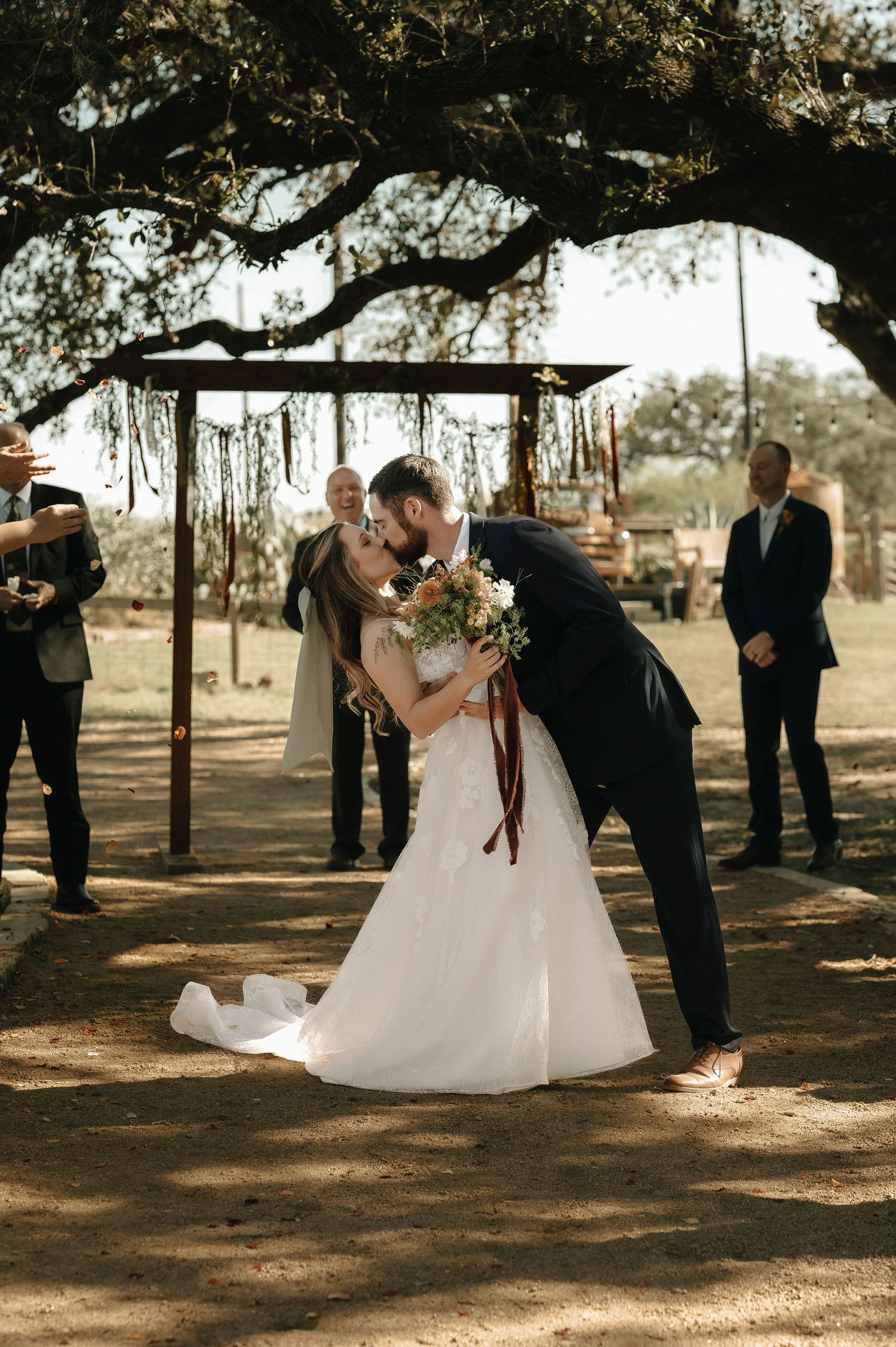 Wedding ceremony moments captured under a rustic wooden pergola with natural lighting.