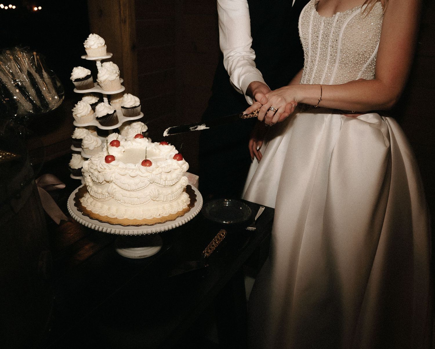 Wedding cake cutting scene in dimly lit reception setting.
