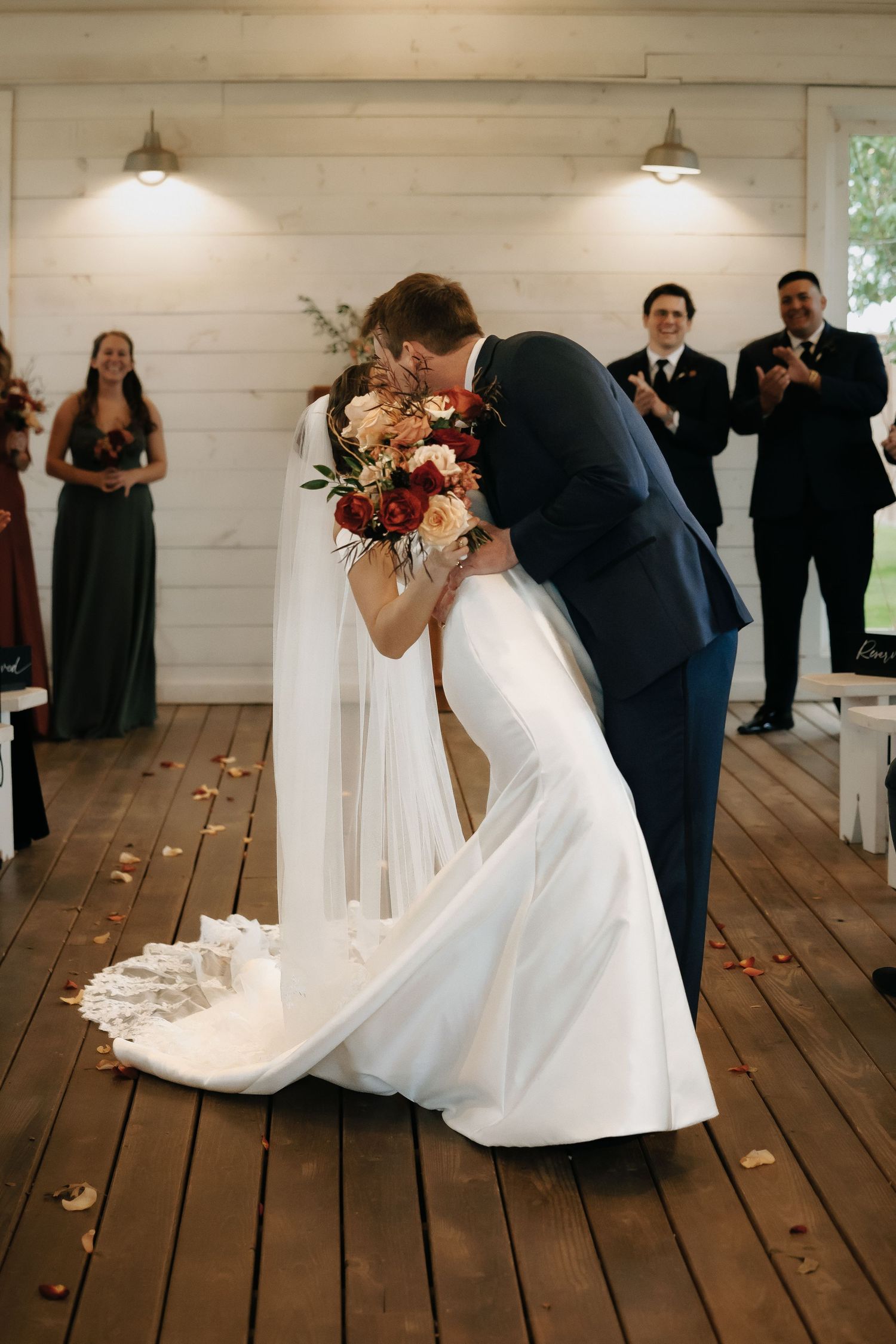 Wedding dance sequence in rustic white venue with wooden floors and rose petals scattered about.
