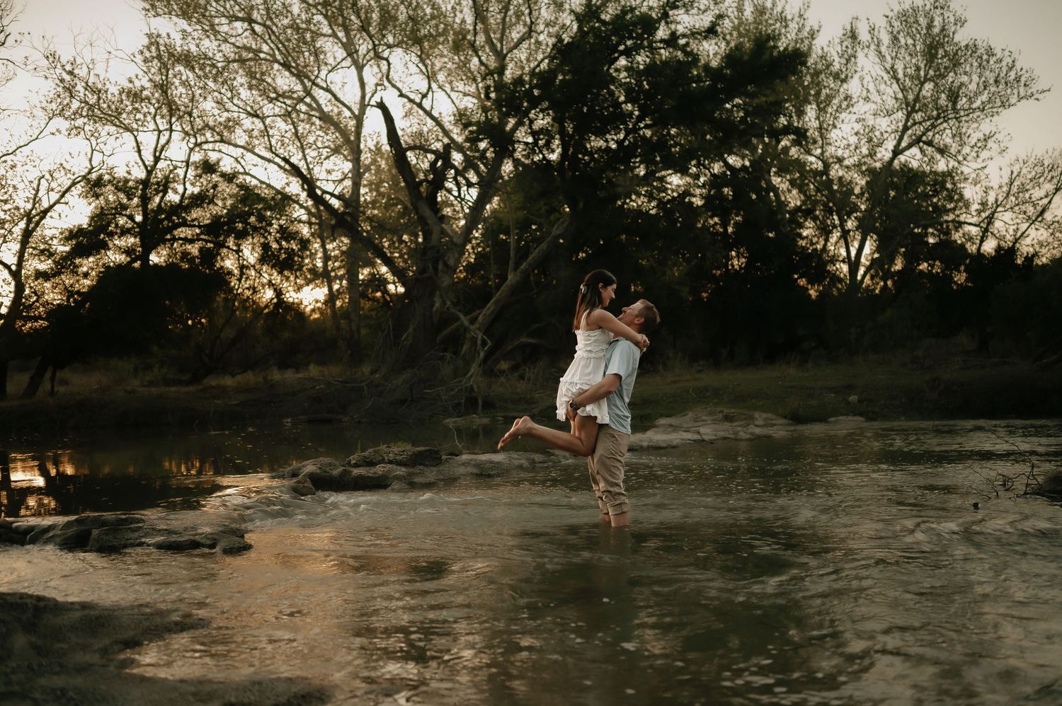 Joyful leap captured against sunset-lit water and trees.